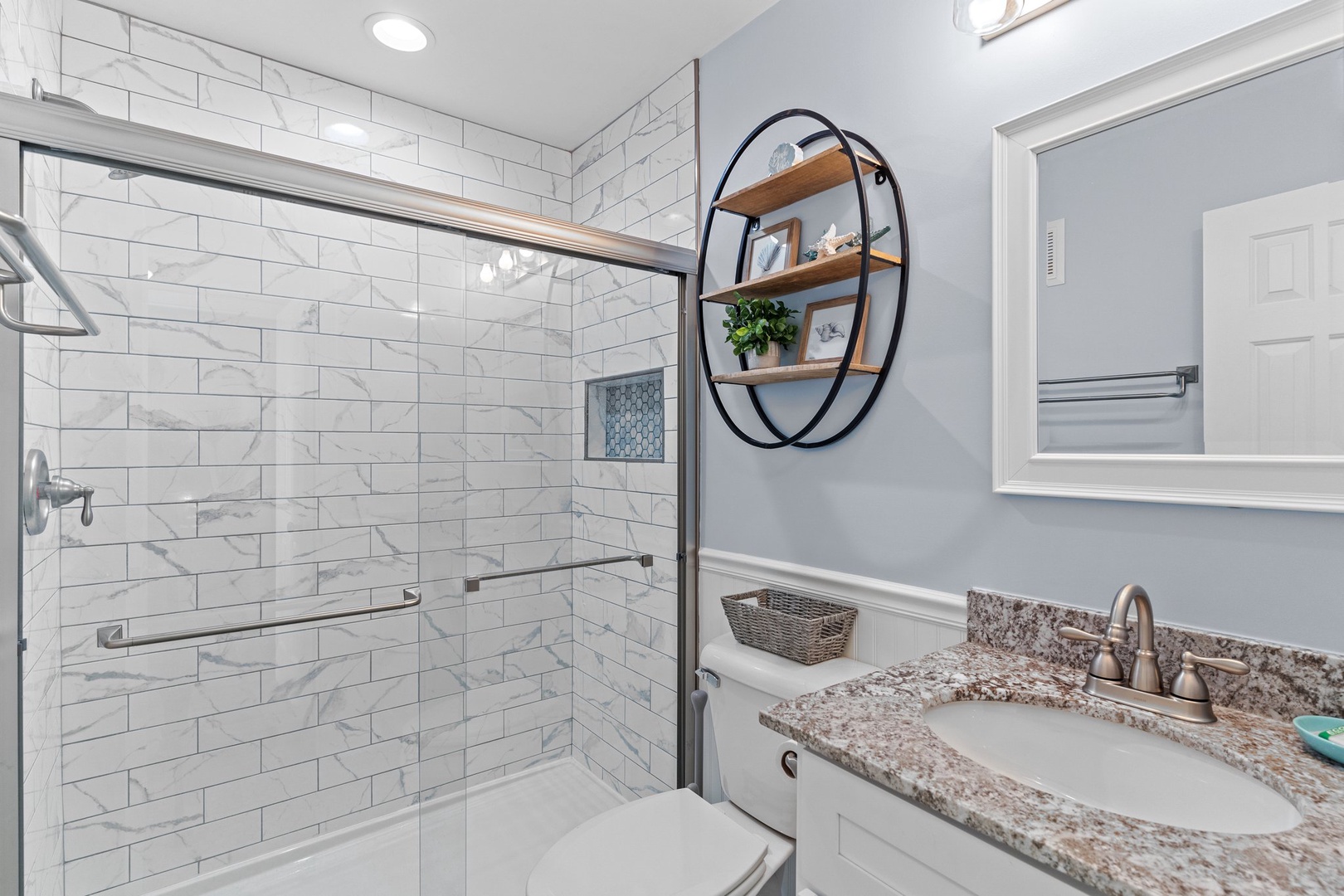 Unwind in your beautifully appointed bathroom with elegant marble subway tile shower, granite countertops, and thoughtful touches like the stylish circular shelf.