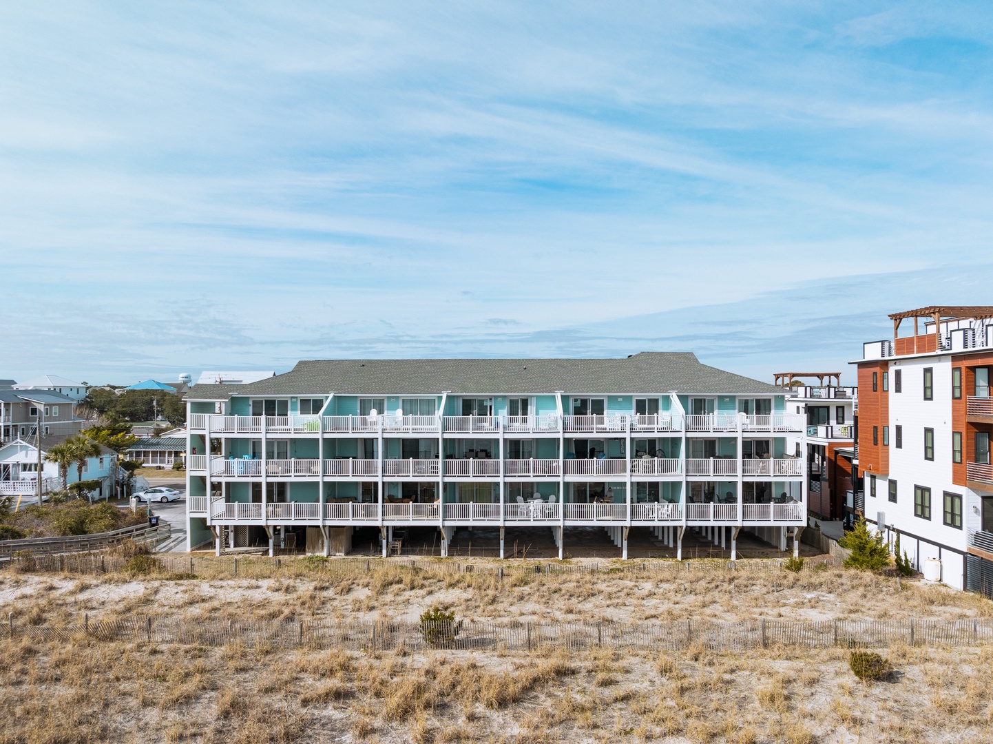Oceanfront property featuring multiple levels of private balconies with beach access and coastal neighborhood surroundings.