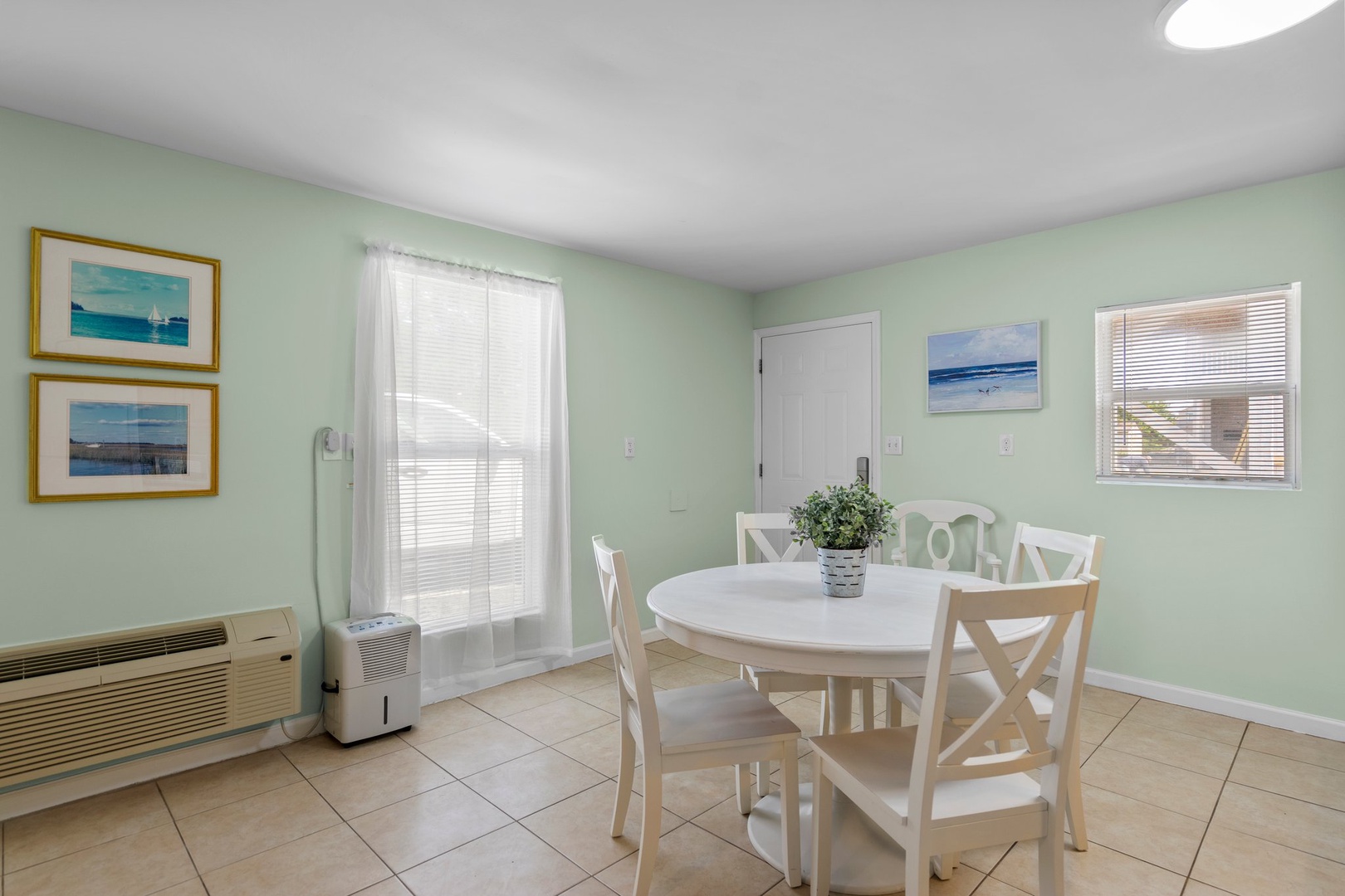 Gather around your bright dining table where coastal artwork and soothing mint walls create the perfect backdrop for memorable meals.