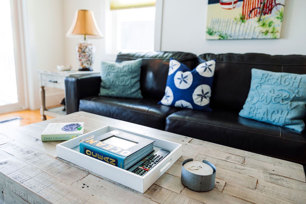 Sink into your comfortable leather sofa and unwind with coastal vibes, beach-themed pillows, and thoughtfully curated books for your perfect getaway.