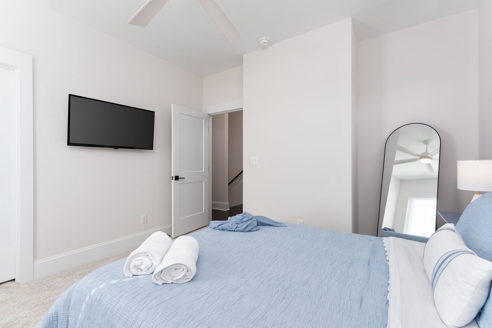 Unwind in your serene bedroom featuring soft blue linens, fresh towels, and modern amenities for the perfect night's rest.