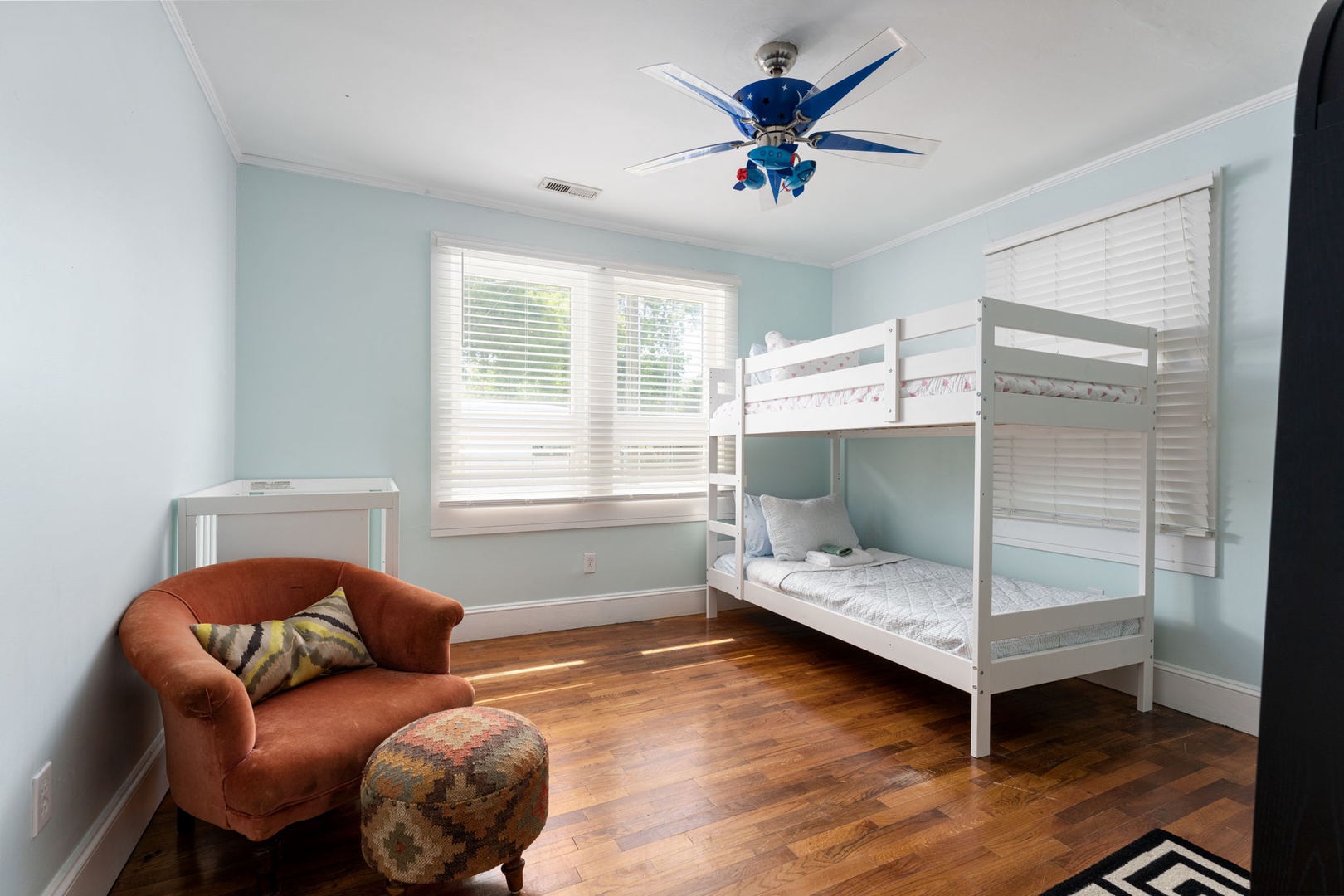 Settle into your cozy bedroom with cheerful blue walls, polished hardwood floors, and a comfortable reading nook by bright windows.