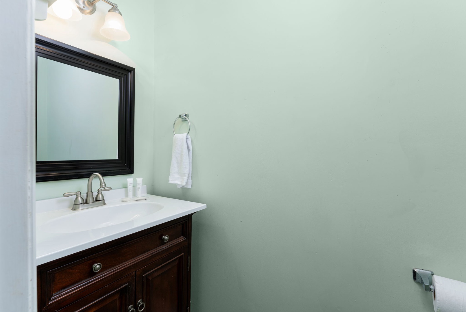 Your private bathroom features a pristine vanity with elegant dark wood cabinetry, crisp white countertops, and fluffy fresh towels—ready for your refreshing morning routine.