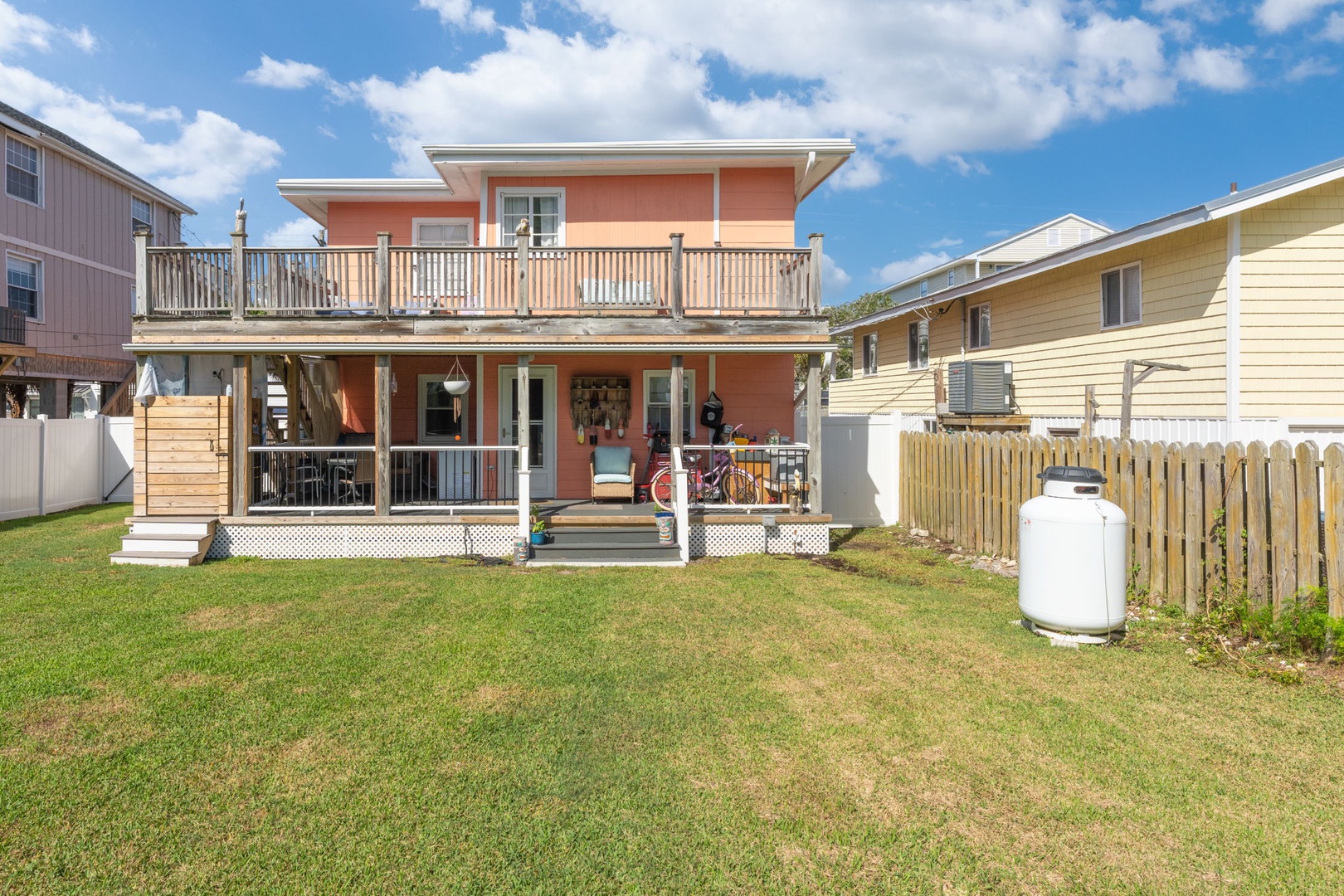 Charming coral-colored beach house with wraparound porches and private yard, nestled in a friendly coastal neighborhood.