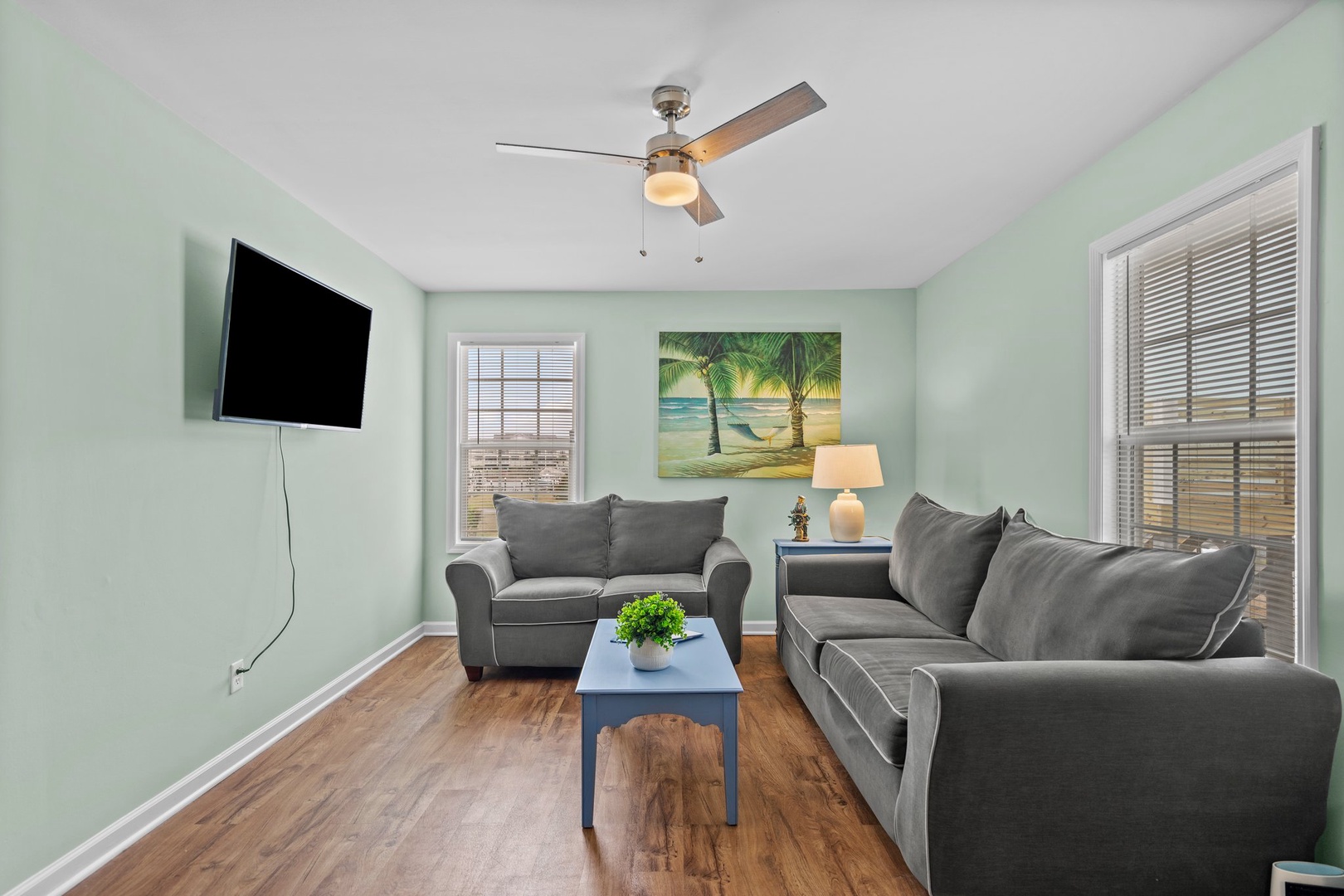 Unwind in your cozy living room with plush seating, tropical artwork, and modern amenities for the perfect relaxing getaway.
