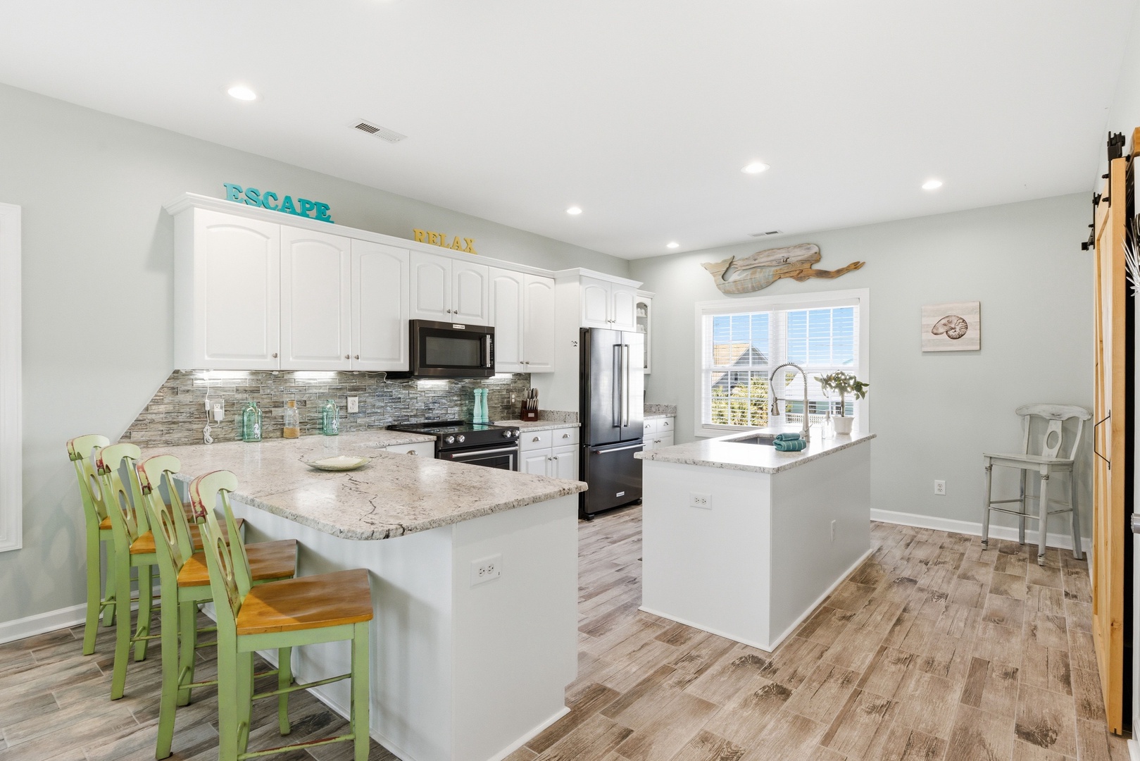 Gather around the bright, fully equipped kitchen with granite countertops and coastal charm. Cheerful bar seating and modern appliances make cooking and conversation easy.