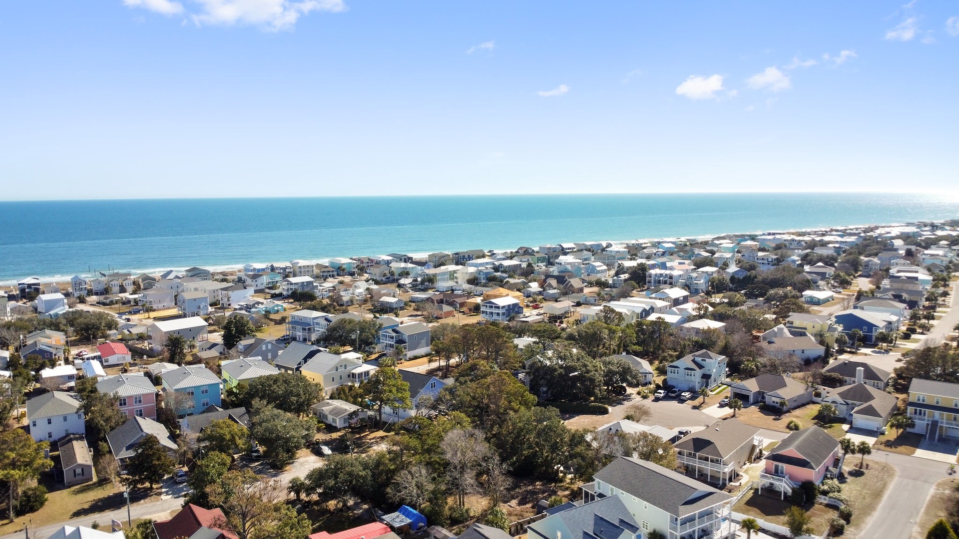 Aerial view of charming coastal community with sandy beaches and turquoise waters stretching to the horizon.