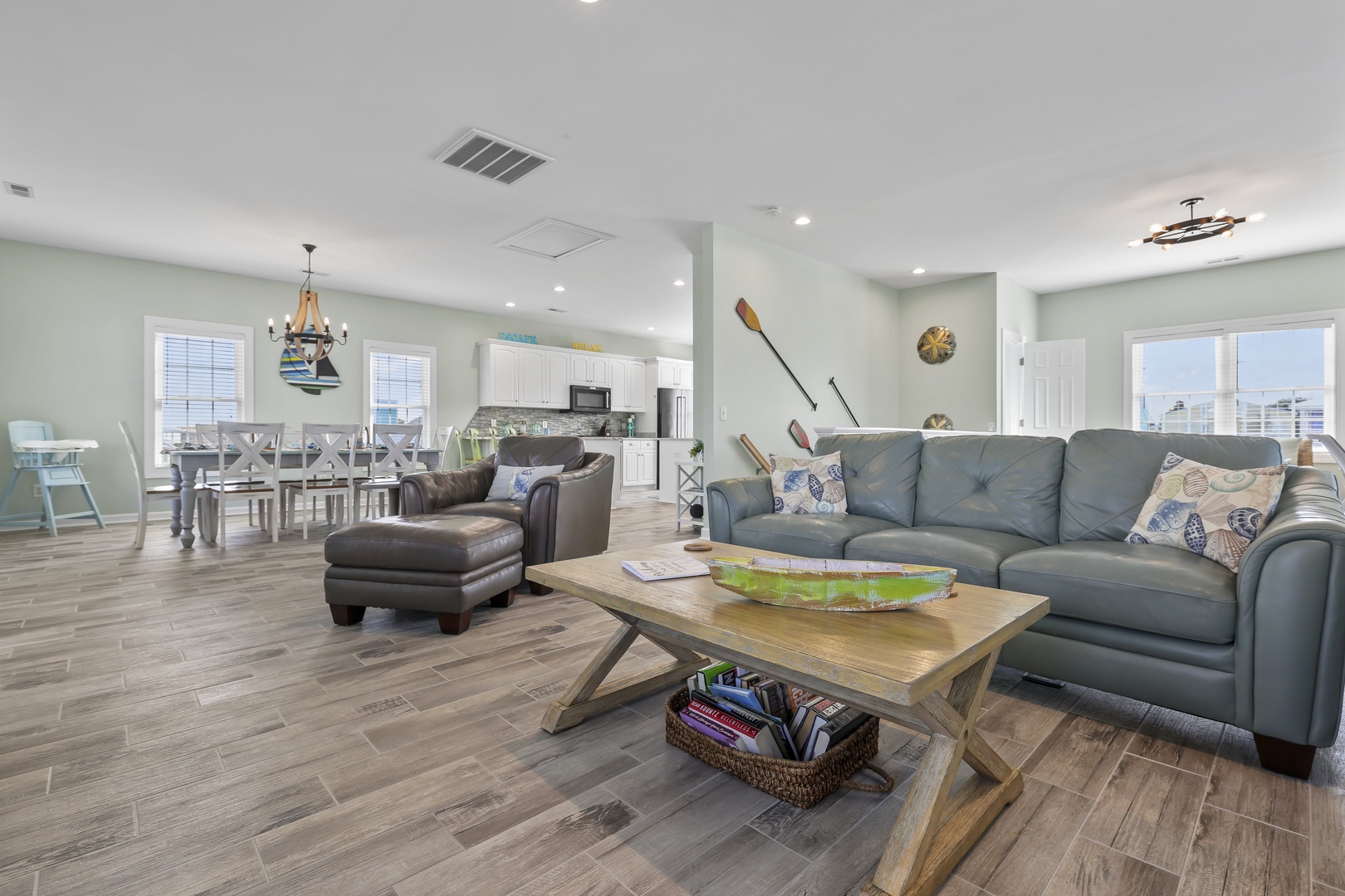 Kick back in your coastal living room where soft leather sofas and nautical touches set the stage for relaxed evenings, flowing into an open kitchen and dining space perfect for gathering.