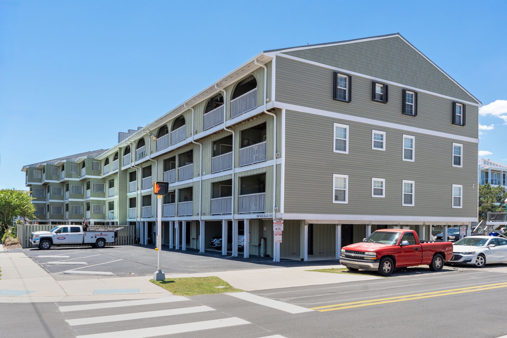 Multi-level vacation property with covered parking and private balconies, located in a coastal area with easy street access and nearby greenery.