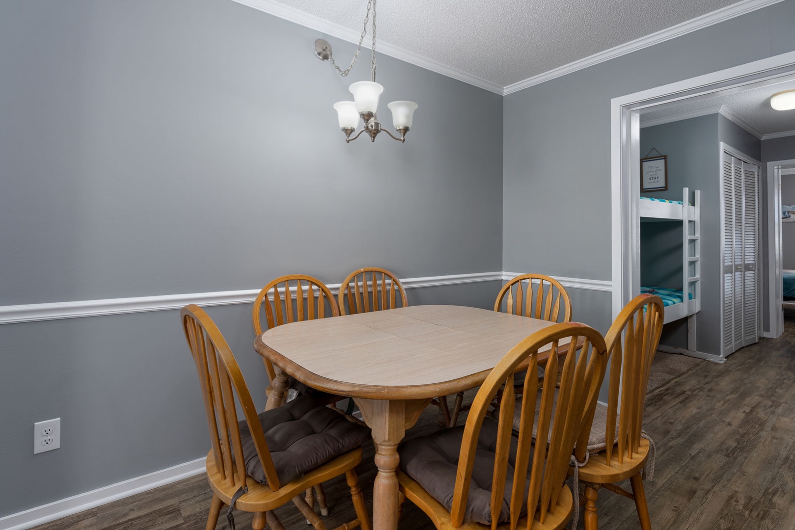 Gather your group around this welcoming dining table, where meals become memories beneath soft chandelier light and calming gray walls.