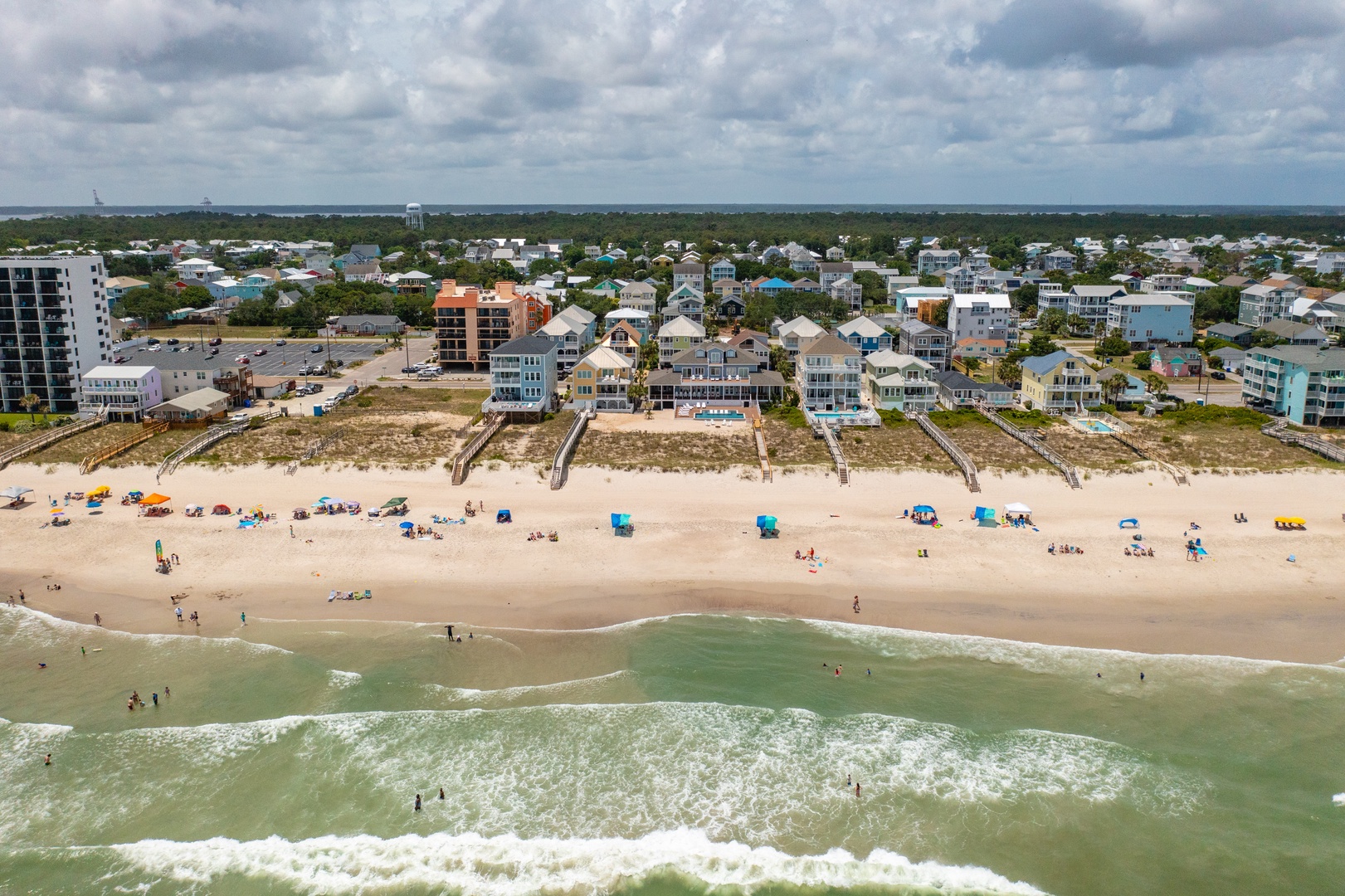 Aerial view of beachfront vacation rentals with direct beach access and rolling waves just steps from colorful coastal homes.
