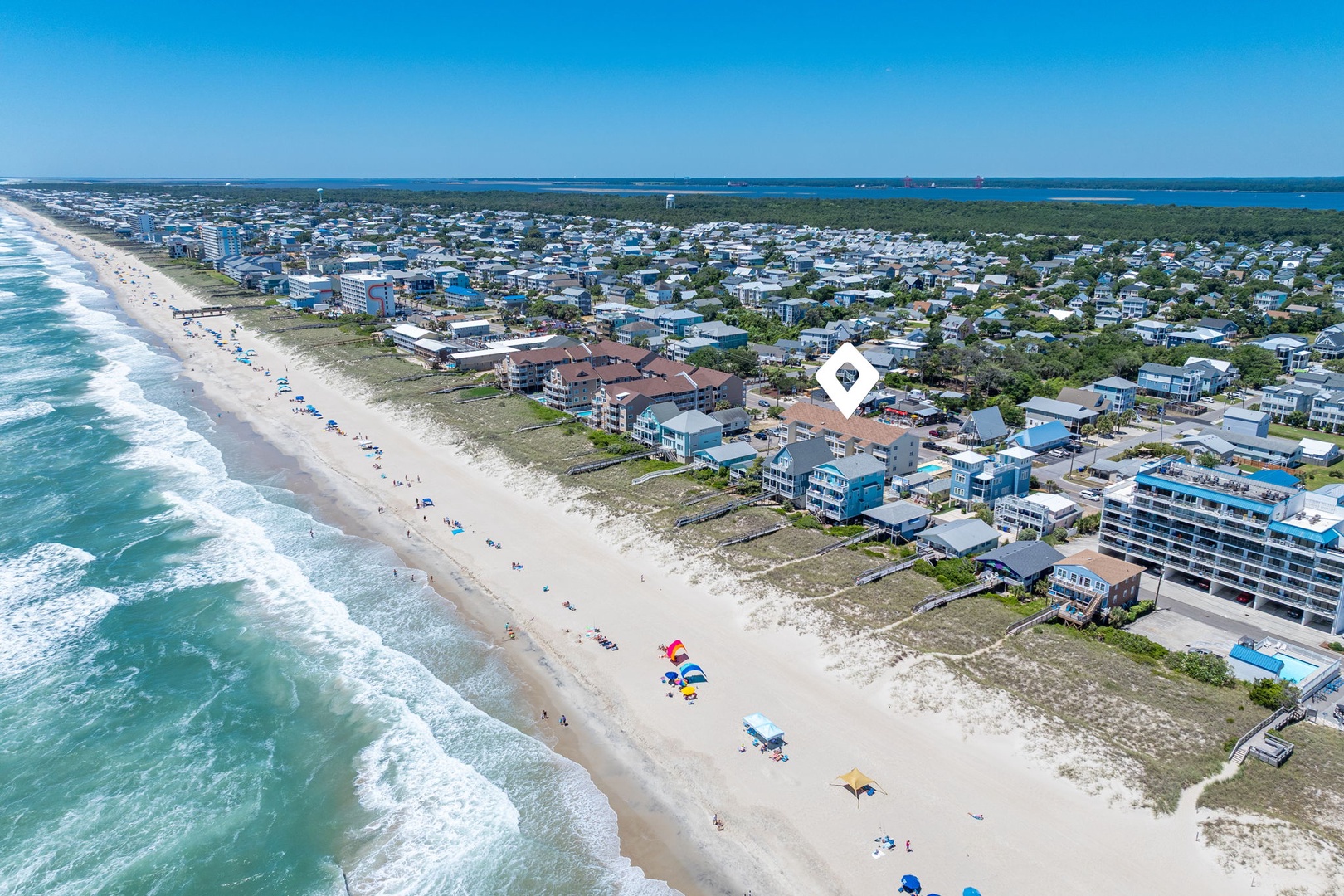 Aerial view of a coastal beach community with pristine sandy shores, residential neighborhoods, and easy access to both ocean and bay waters.