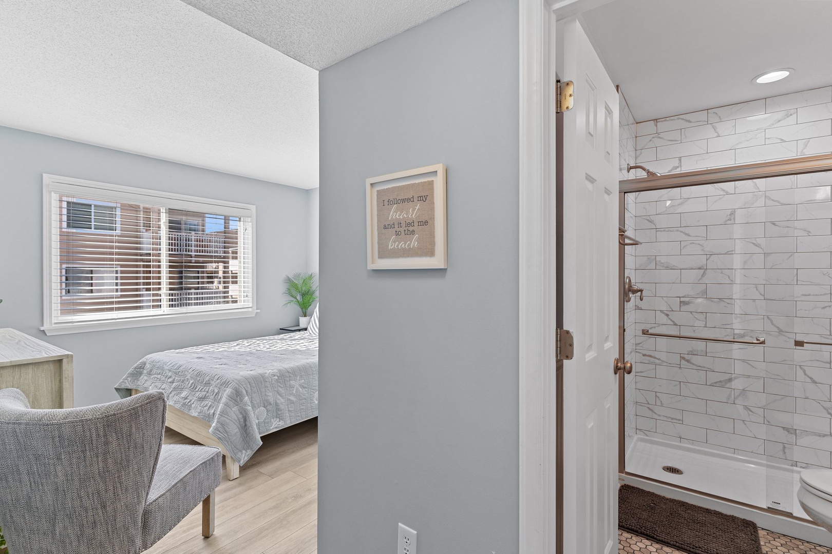 Relax in your beautifully appointed bedroom with coastal charm, complete with an elegant ensuite shower featuring modern subway tile and warm fixtures.