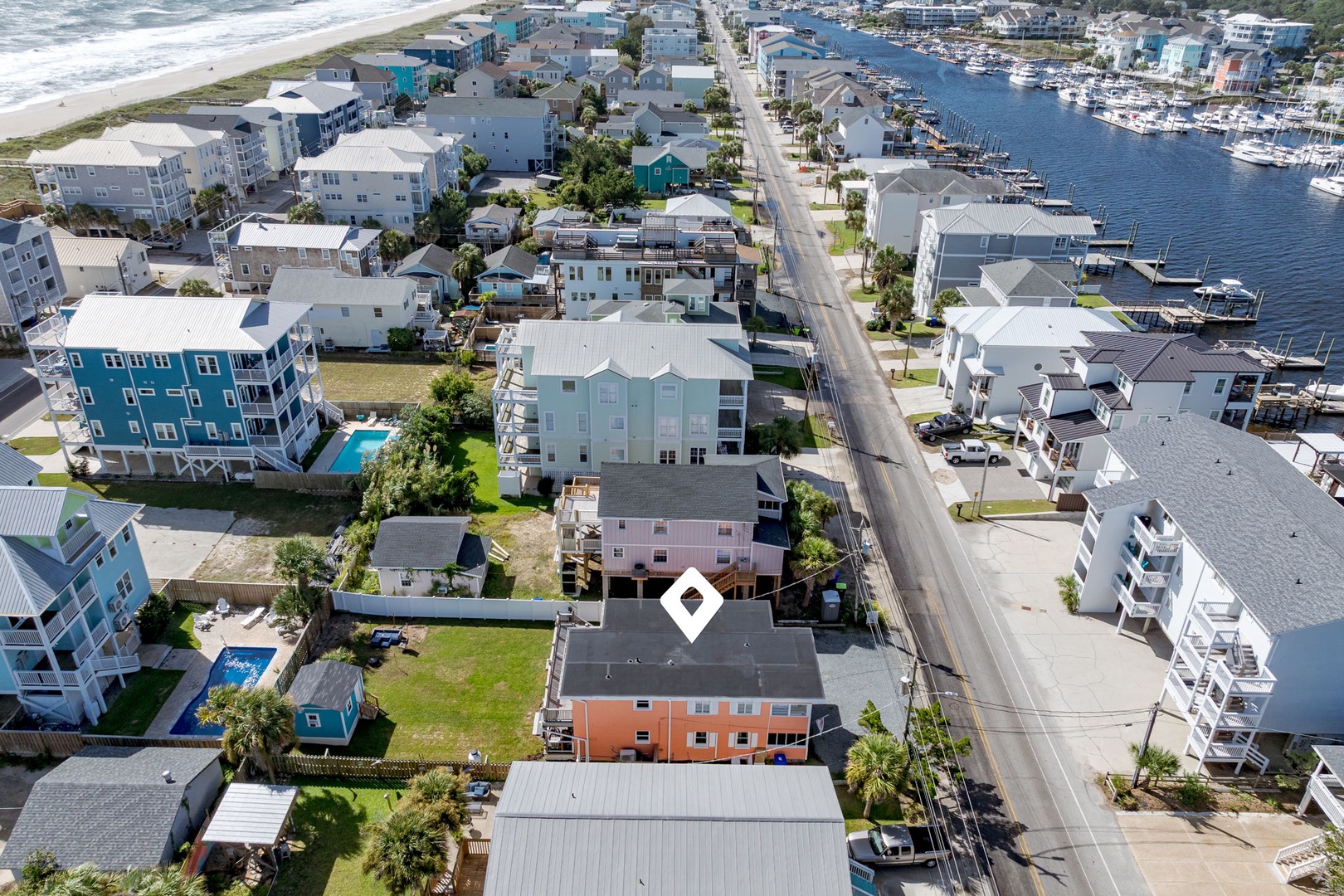 Aerial view of charming coastal neighborhood featuring colorful beach houses, marina access, and oceanfront proximity.