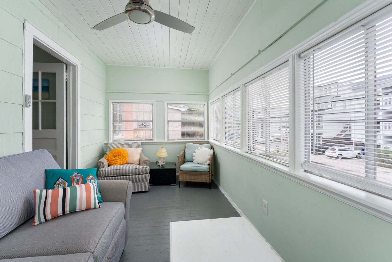 Unwind in your bright sunroom with comfy seating and refreshing mint-green walls that catch the gentle breeze from the ceiling fan.