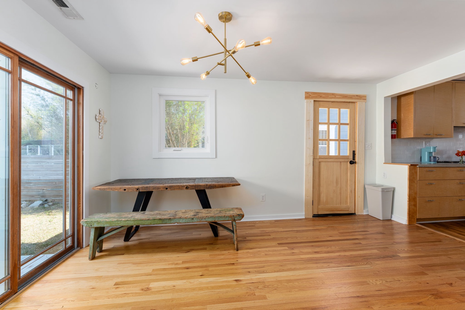 Gather around this rustic dining table where your group can share meals under the warm glow of modern lighting, with garden views through expansive windows.
