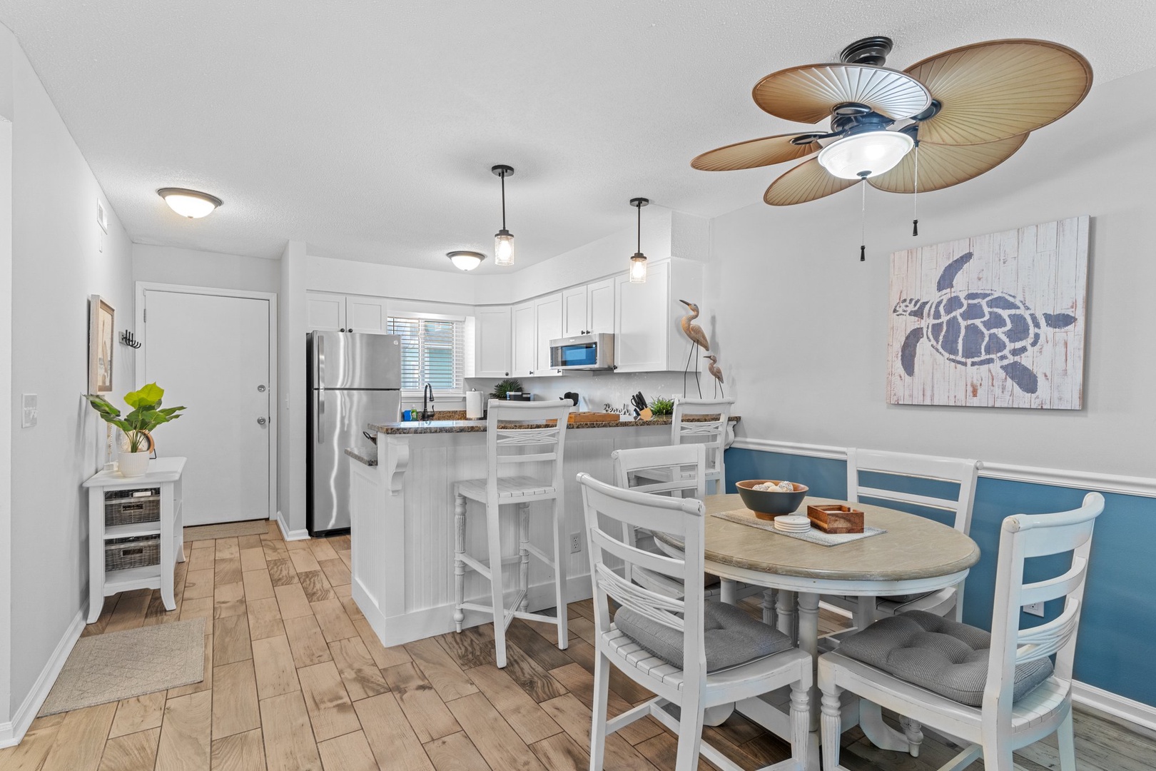 Gather around your coastal kitchen with tropical ceiling fans, modern appliances, and charming dining space perfect for memorable meals together.