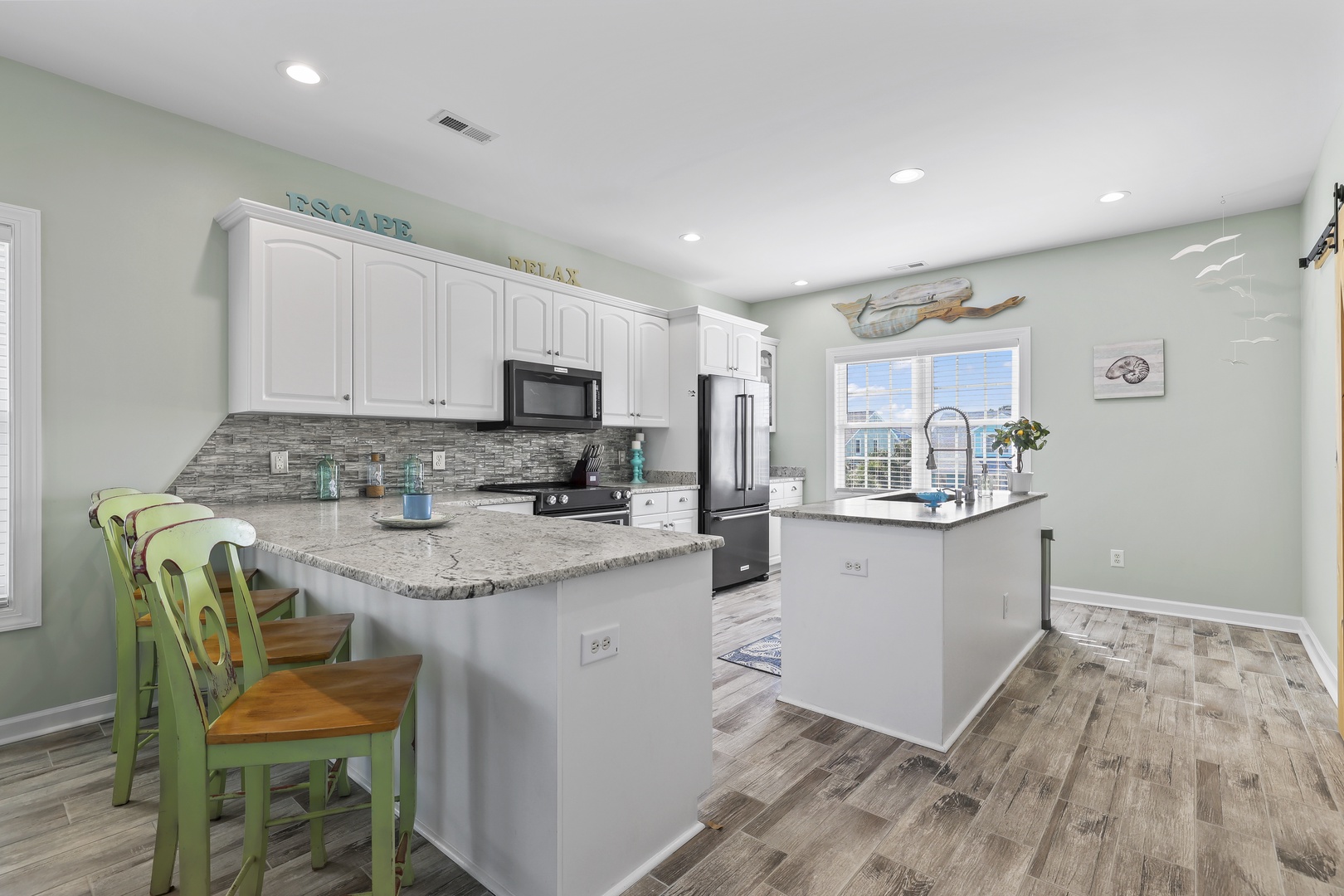 Your fully equipped kitchen invites you to cook and gather, with coastal charm in every detail—from granite countertops to cheerful bar seating overlooking the bright, open space.