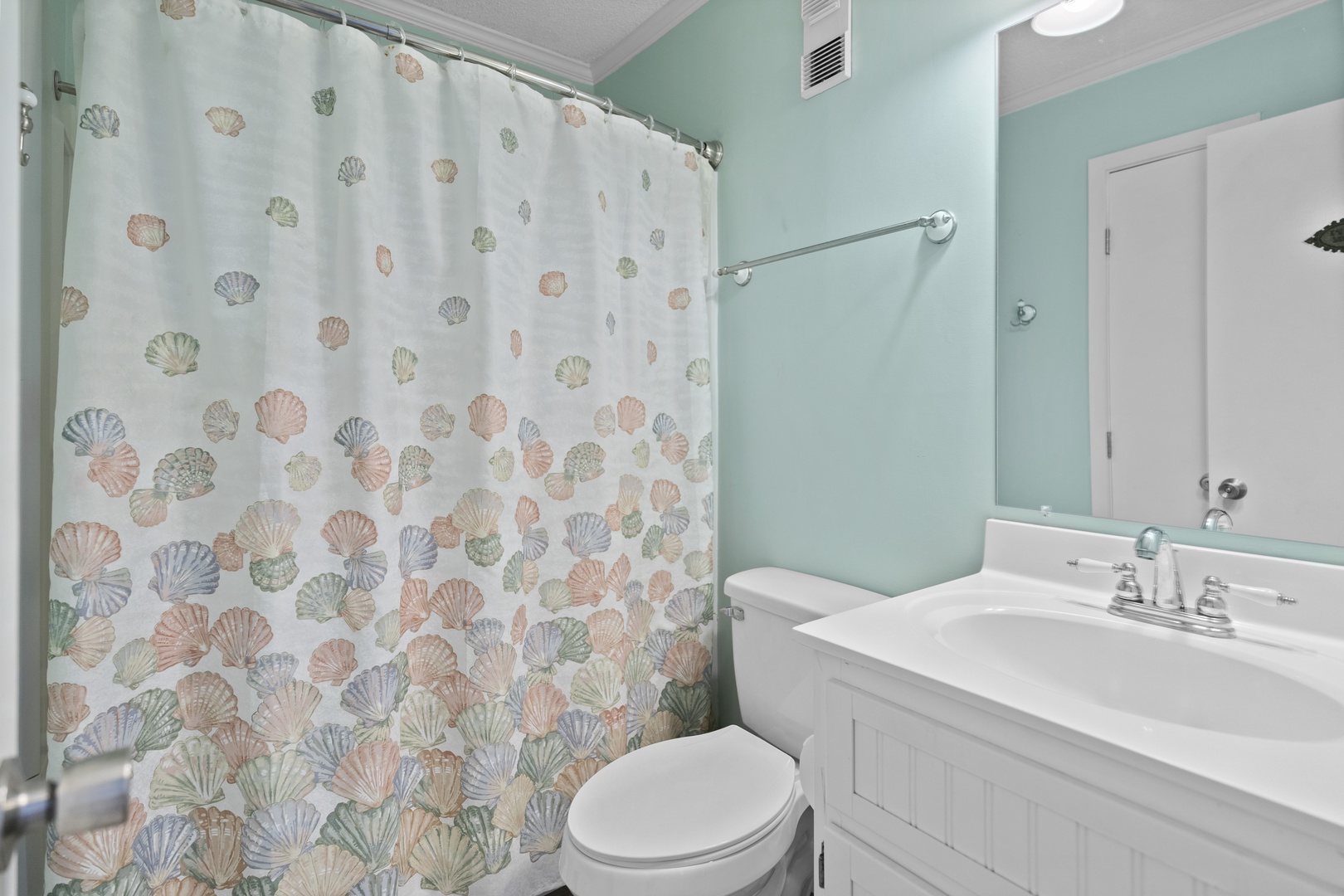 Refresh in your coastal-themed bathroom with cheerful seashell shower curtain and soothing mint walls that transport you to seaside tranquility.