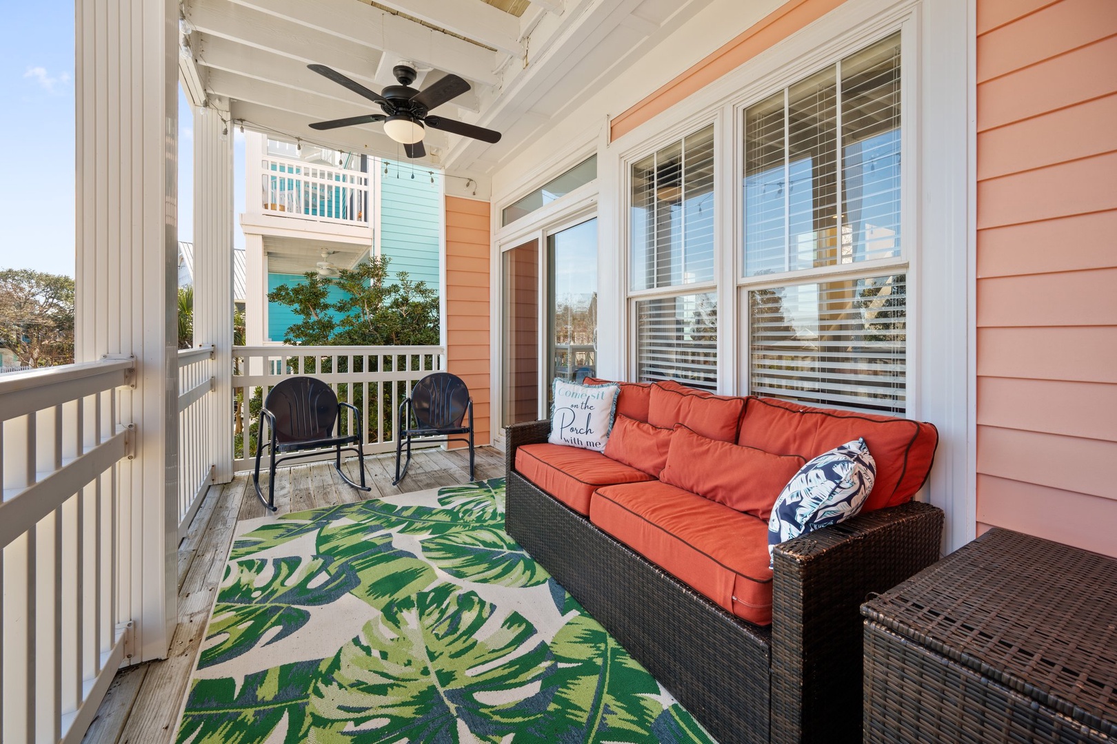 Relax on your covered porch with bright coral cushions and tropical vibes, where the ceiling fan keeps you cool.