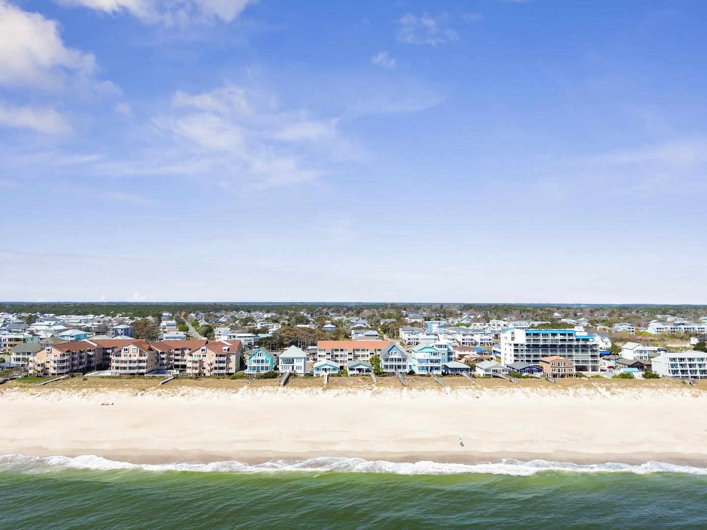 Aerial view of beachfront properties with pristine sandy shores and gentle waves creating an idyllic coastal setting.