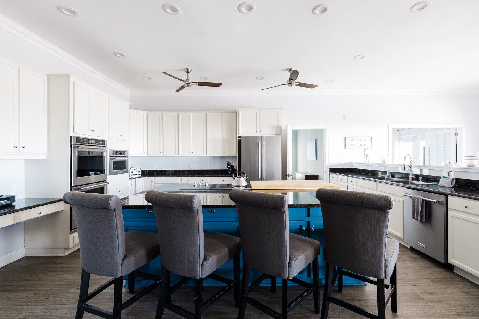 Cook and gather in your spacious gourmet kitchen with bright white cabinetry, sleek granite countertops, and a vibrant blue island.