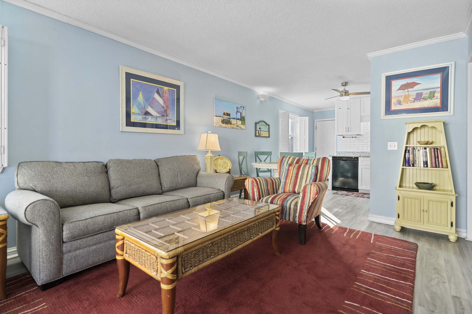 Sink into the plush gray sofa and enjoy your morning coffee in this bright, coastal-themed living space with charming nautical artwork.