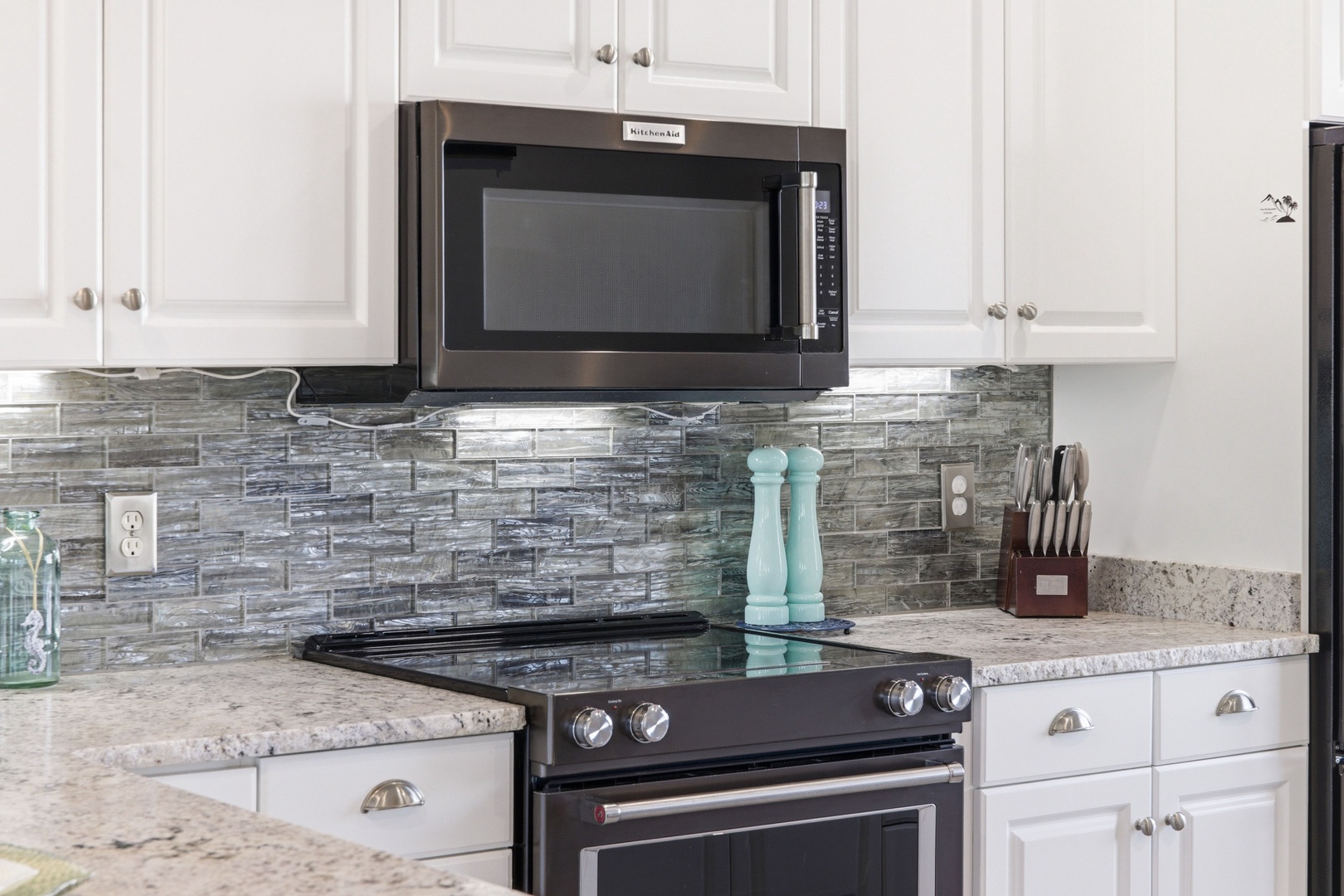 Cook your favorite meals in this well-equipped kitchen featuring stainless steel appliances, granite countertops, and stylish glass tile backsplash, plus everything you need to feel right at home.
