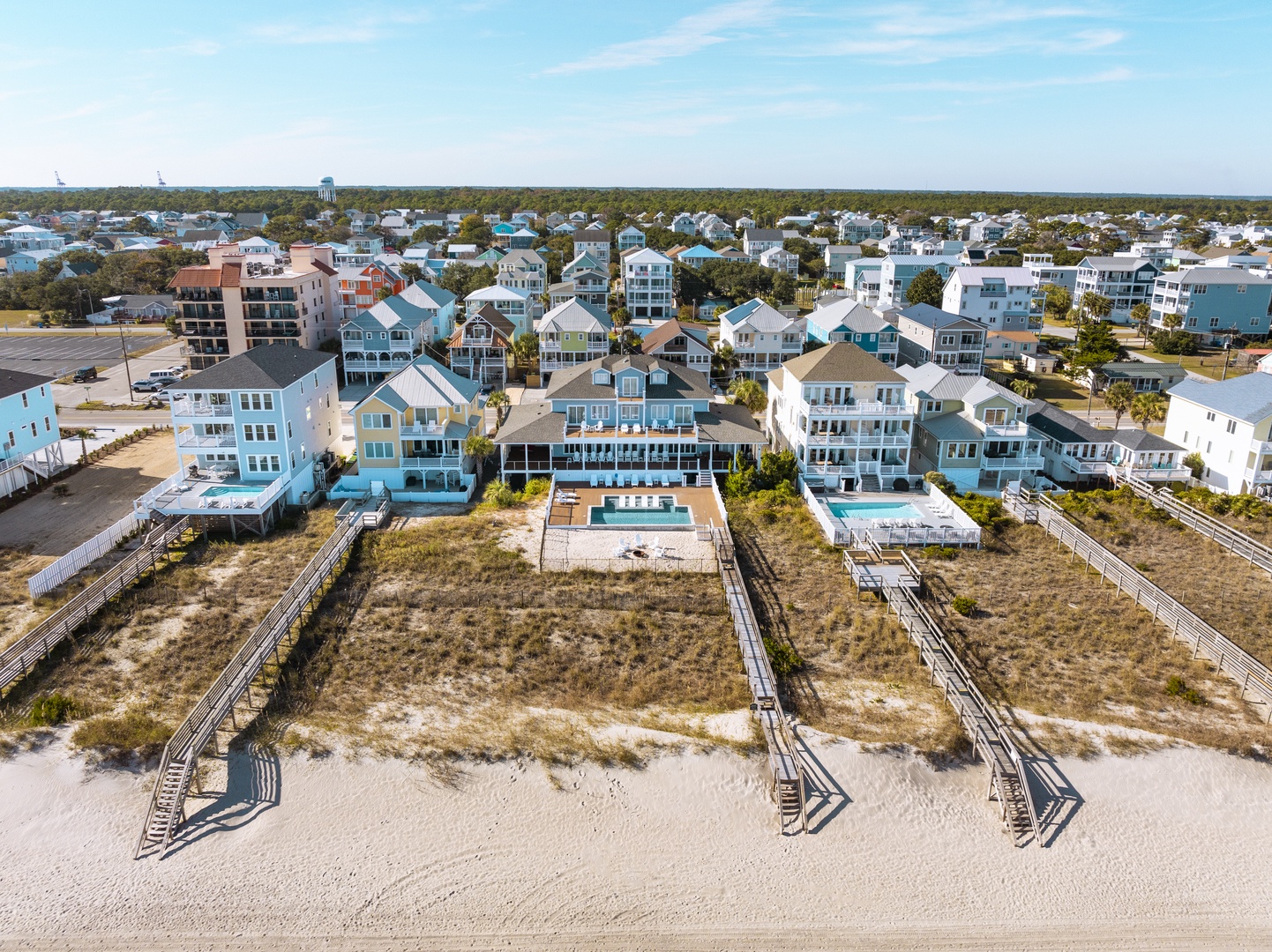 Oceanfront vacation homes with private pool and beach access via wooden boardwalk in coastal community.