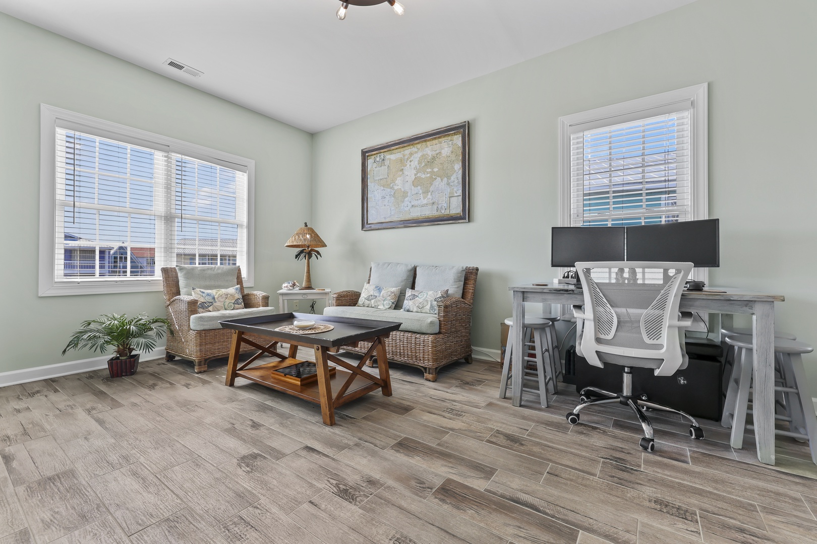 Settle into your bright work-and-relax space with comfortable seating, wood-style floors, and large windows filling the room with natural light.