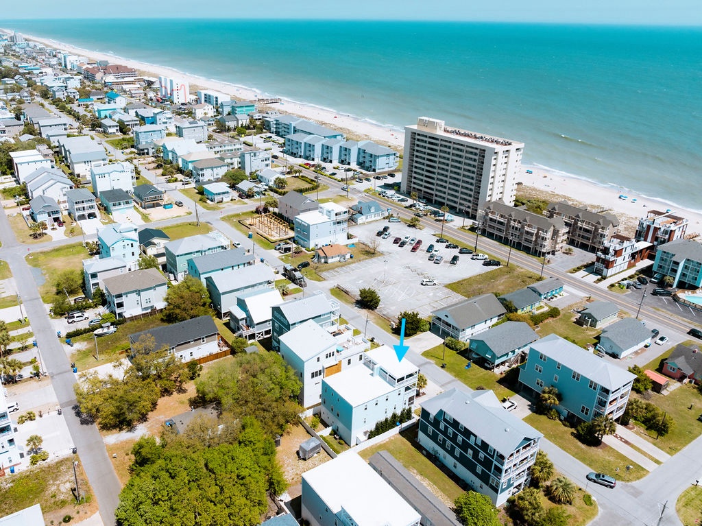 Aerial view of a coastal beachfront community with colorful homes, nearby hotels, and pristine sandy shores stretching along turquoise waters.
