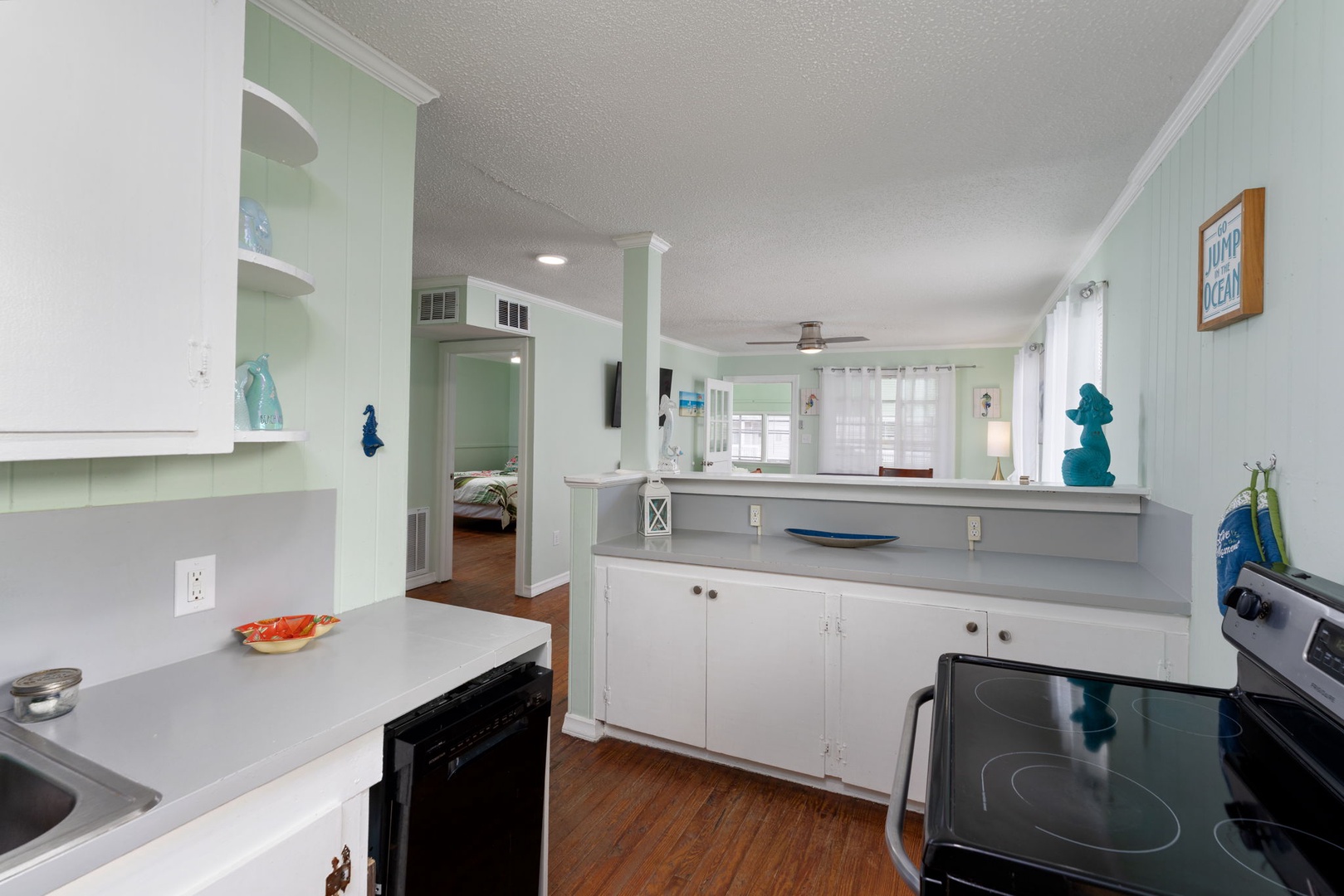 Your bright, coastal-themed kitchen flows seamlessly into the living area, creating perfect space for preparing meals and gathering together.
