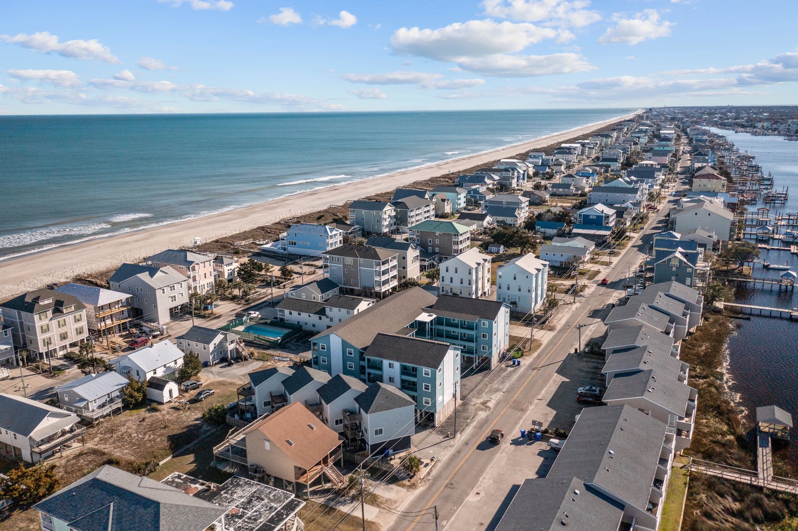 Aerial view of beachfront vacation rental community featuring diverse coastal homes along pristine sandy shores.