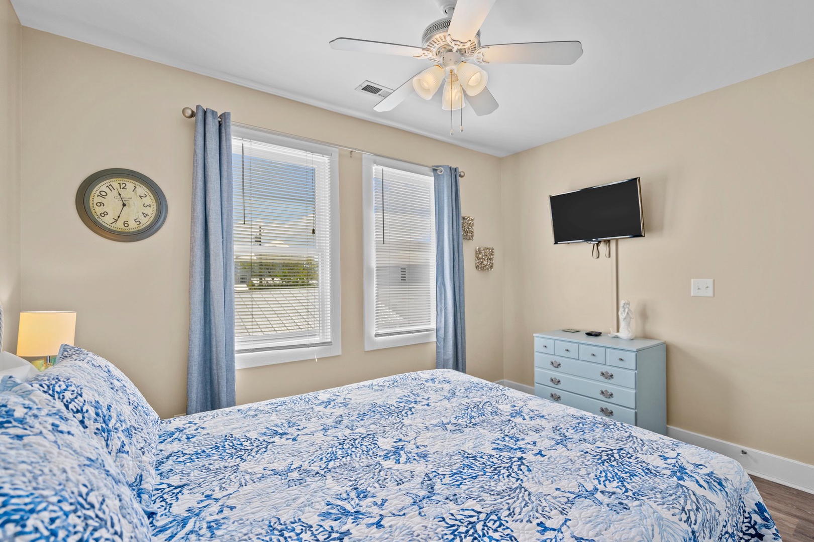 Relax in your peaceful bedroom with comfortable bedding, natural light, ceiling fan, and entertainment center for cozy evenings.