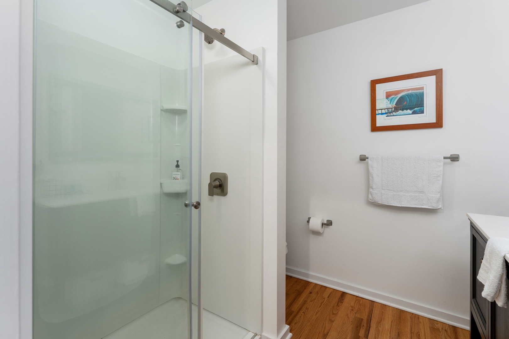 Step into your private oasis with a sleek glass shower, plush towels, and coastal artwork creating a spa-like retreat.