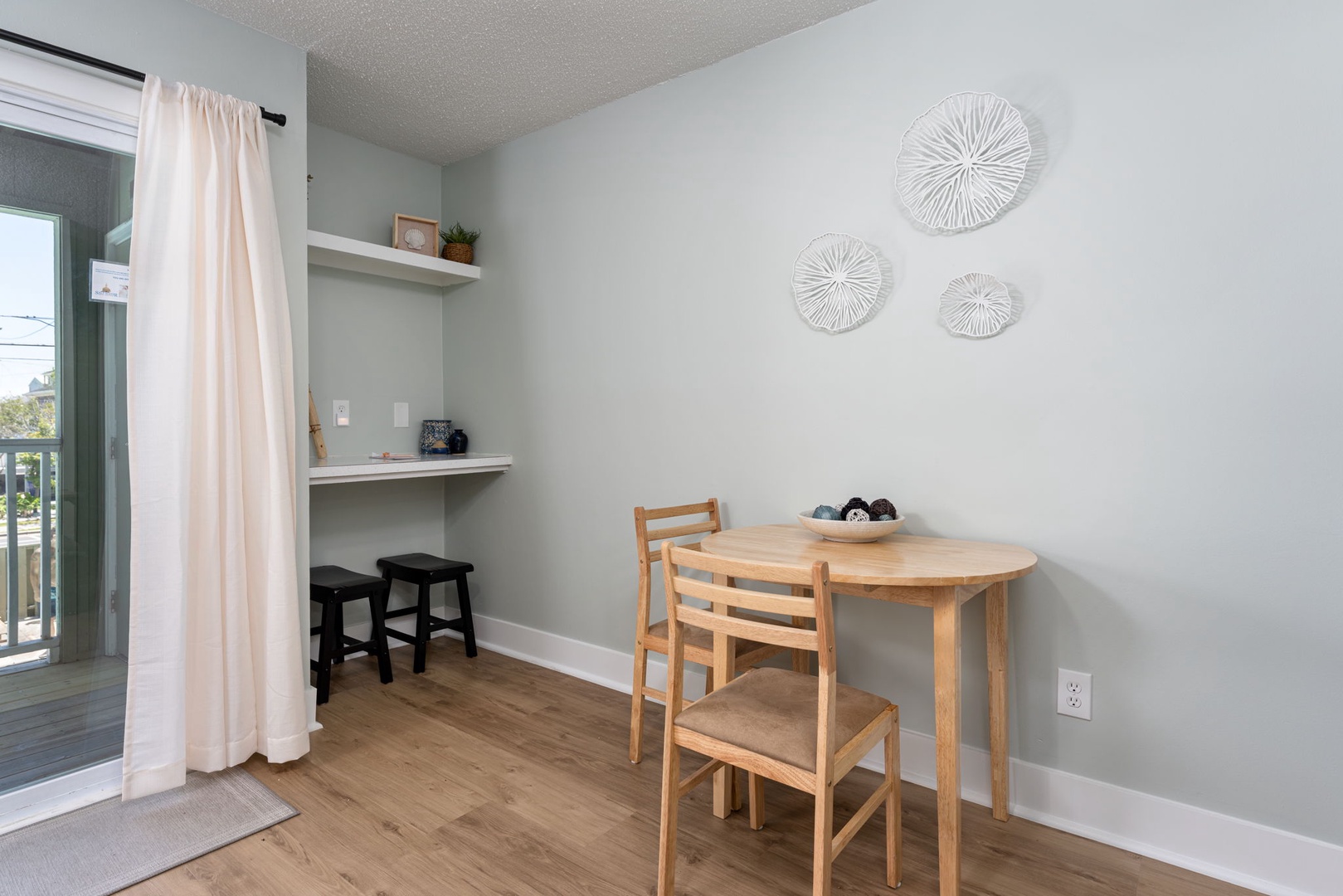 Your cozy breakfast nook awaits with a sunlit dining space where you can savor morning coffee while enjoying natural light streaming through nearby balcony doors.