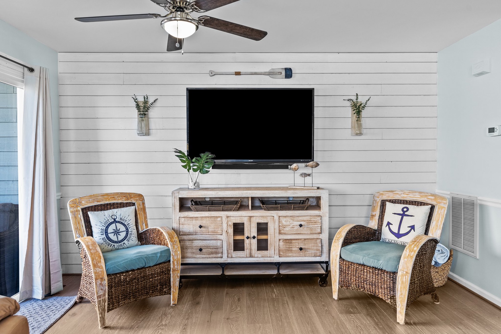 Unwind in your coastal living room where nautical charm meets modern comfort—cozy wicker chairs and shiplap walls create the perfect beach retreat.