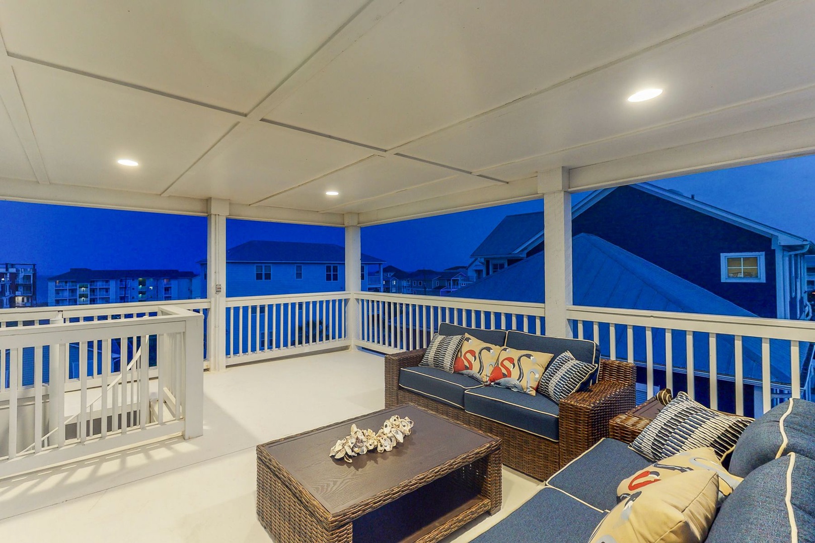 Unwind on your private covered terrace with cozy seating, perfect for evening conversations under soft lighting with neighborhood views.