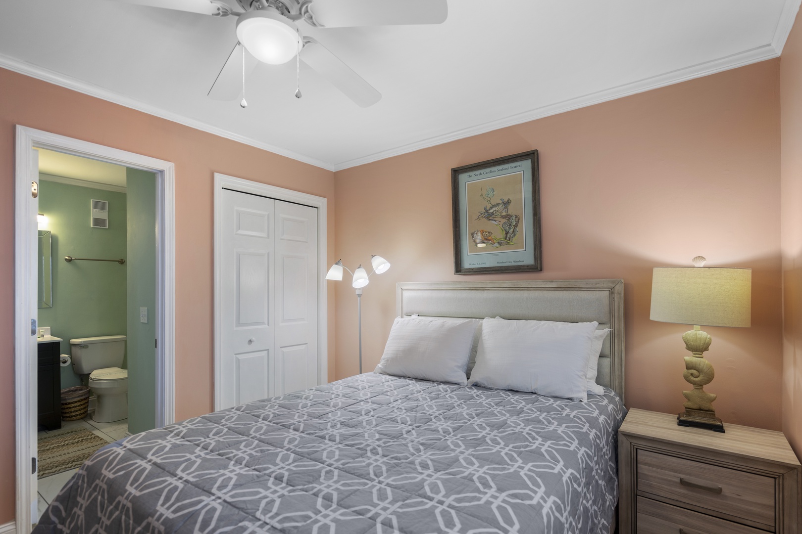 Sink into plush pillows under gentle ceiling fan breezes in your cozy peach-toned bedroom sanctuary, with private bathroom steps away.