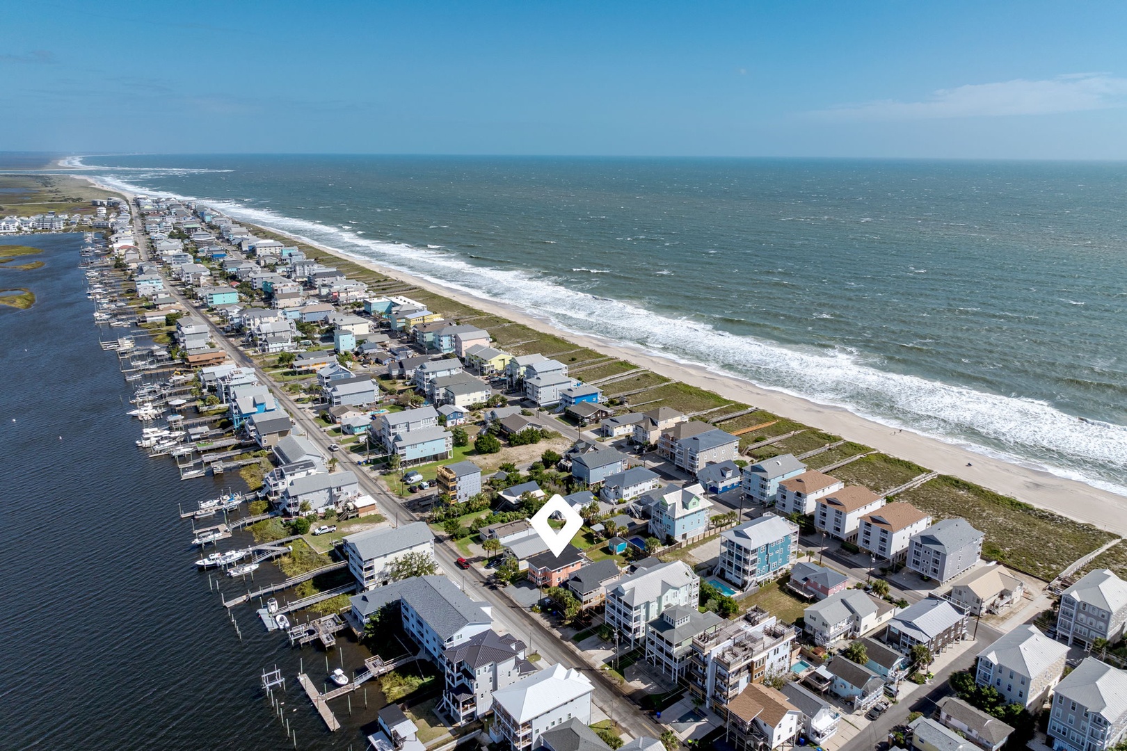 Aerial view of beachfront community featuring oceanfront homes and bay-side properties along pristine coastline.