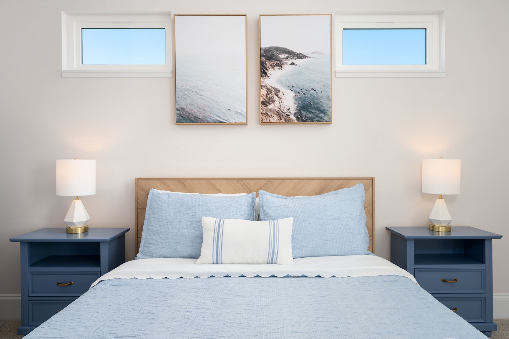 Drift off to sleep in this serene bedroom with coastal artwork and soft blue linens that echo ocean tranquility.