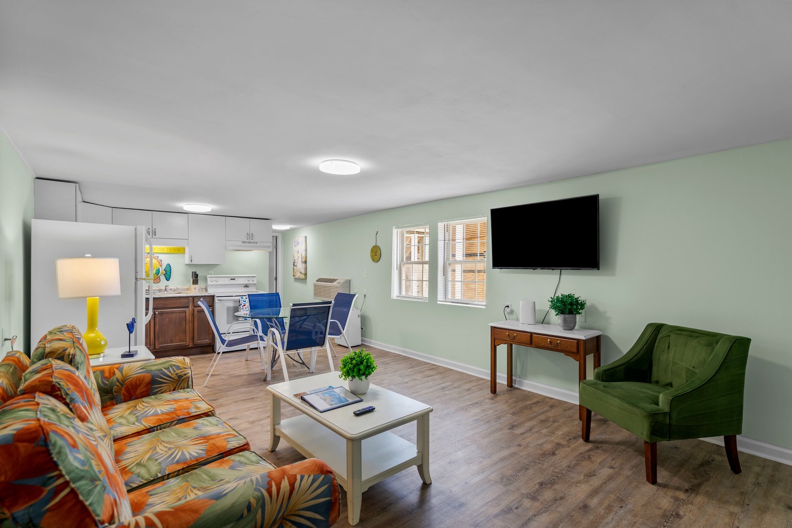 Step into your bright, cheerful living space where tropical-print sofas and calming green walls create the perfect home base for relaxation.