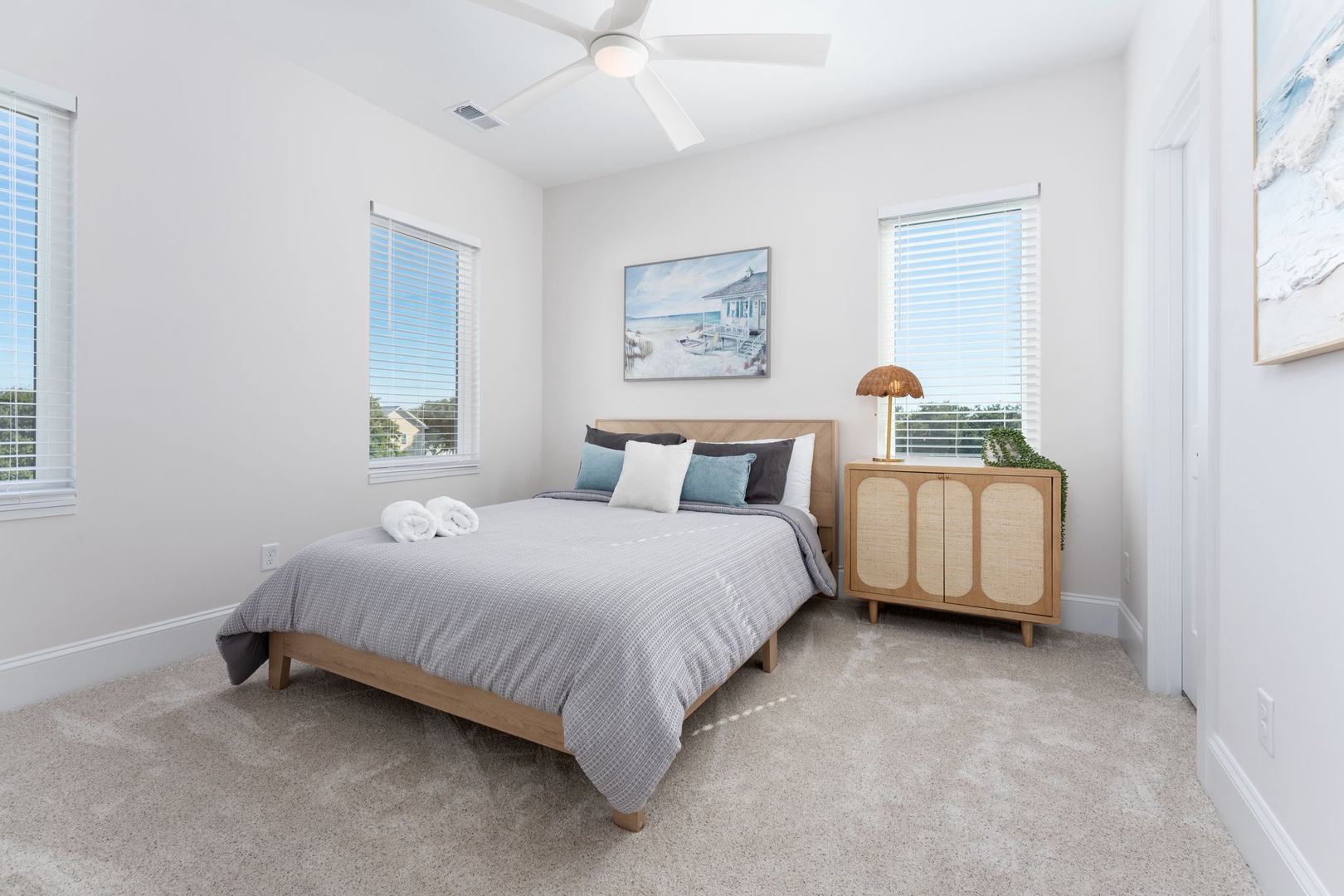 Unwind in this serene bedroom where soft linens and coastal artwork create your perfect retreat after exploring.