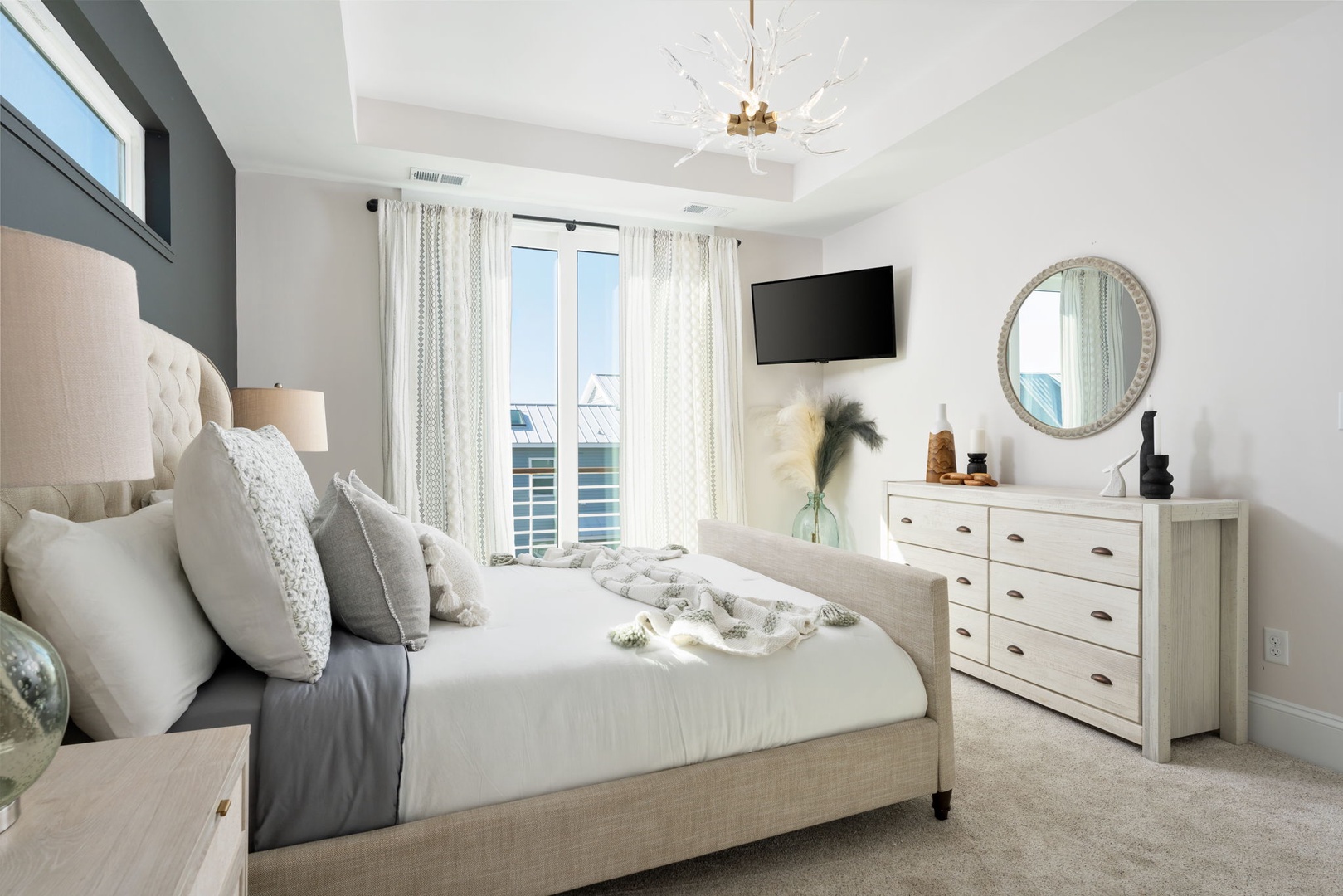 Sink into this serene bedroom's plush linens and wake to natural light streaming through elegant curtains.