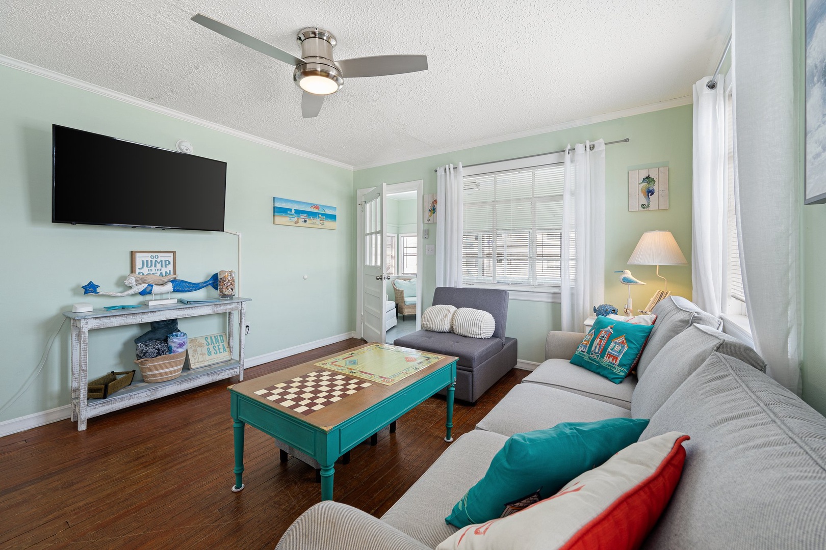 Unwind in your coastal-themed living room with comfortable seating, games, and beach decor creating the perfect vacation atmosphere.