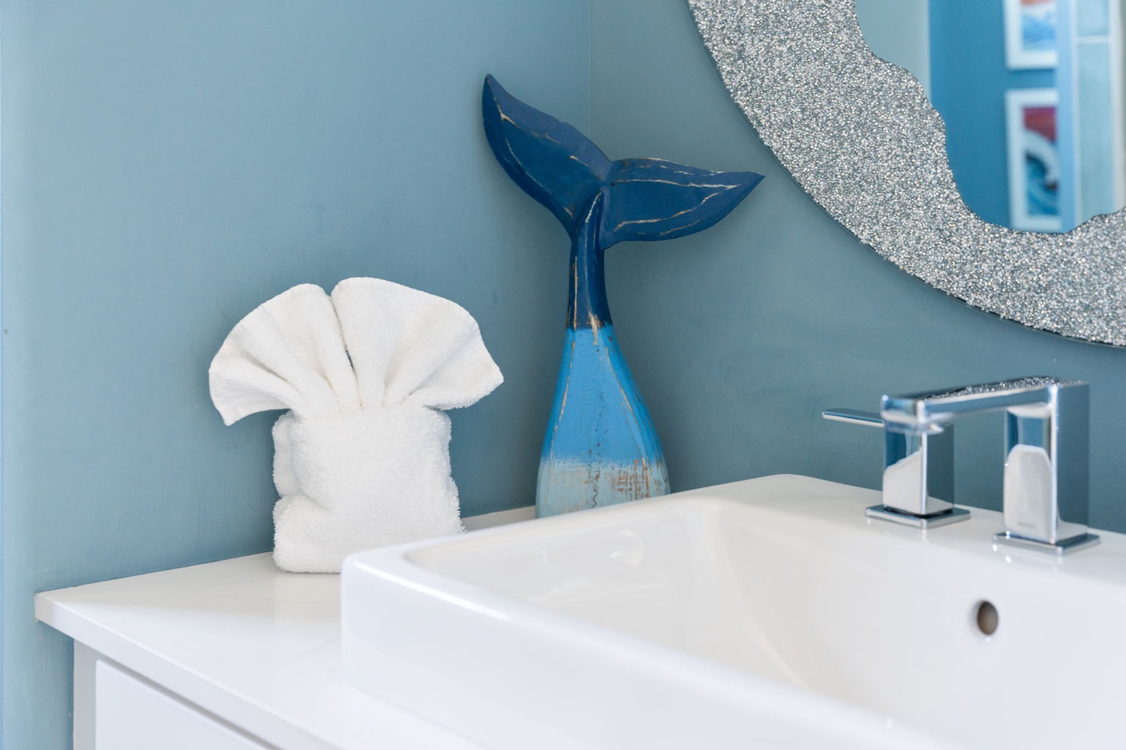 Your stylish bathroom features ocean-themed touches with crisp white linens and modern fixtures for a refreshing coastal vibe.