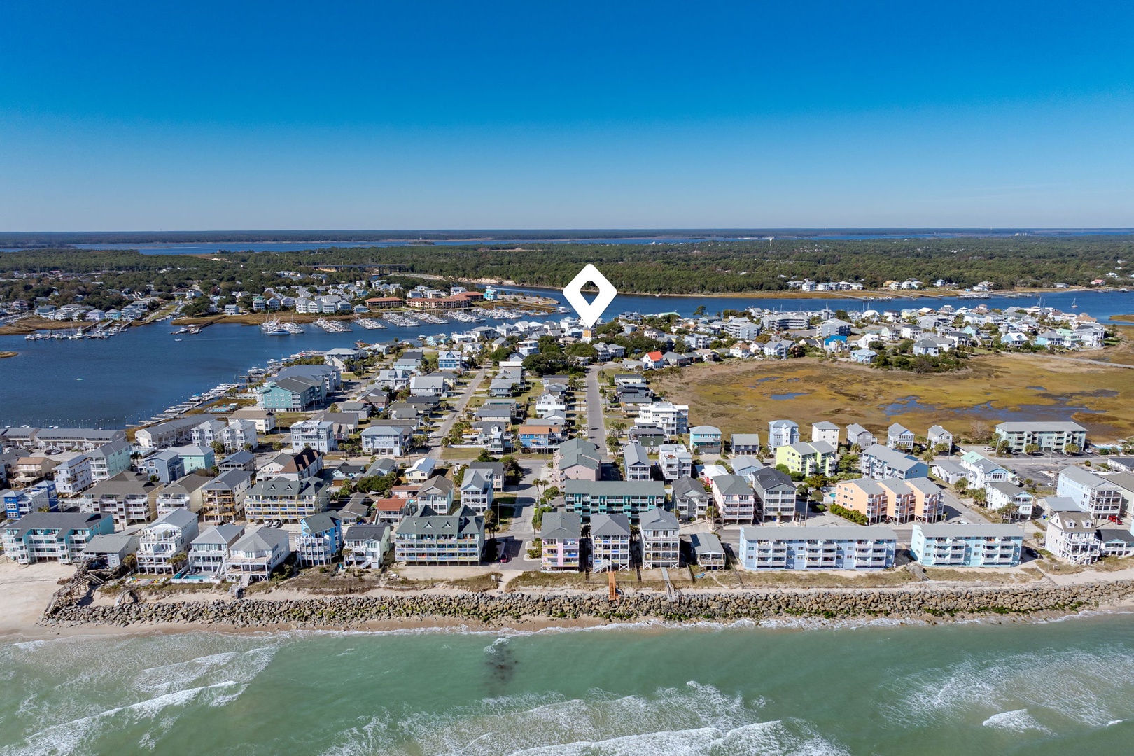 Aerial view of coastal vacation rental community featuring beachfront properties, marina access, and pristine shoreline along scenic waterfront.