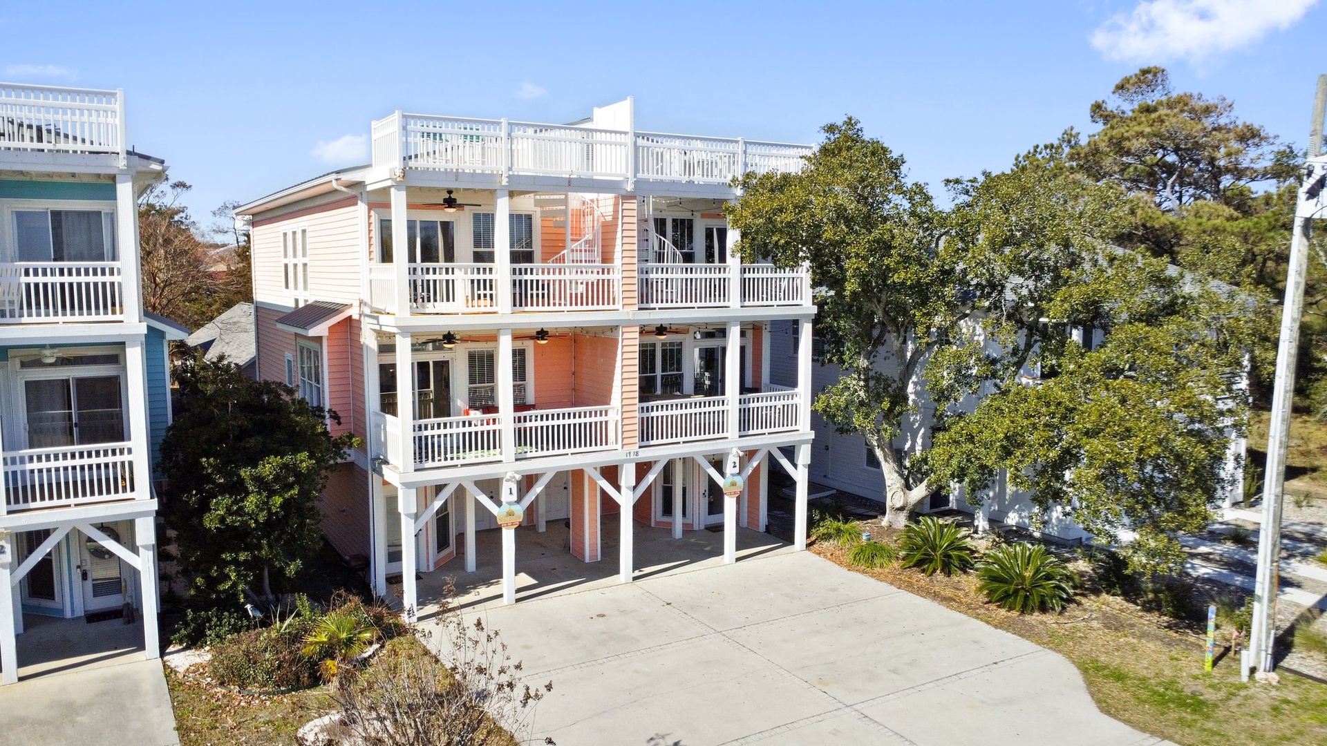 Charming coastal property with elevated design and white railings, nestled among mature trees in a peaceful residential setting.
