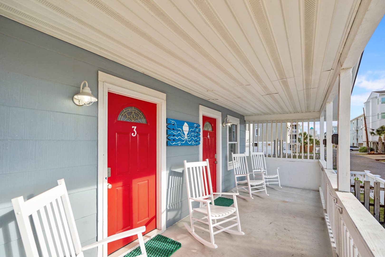 Your charming covered porch beckons with classic white rockers where you can unwind and watch the coastal neighborhood come alive.