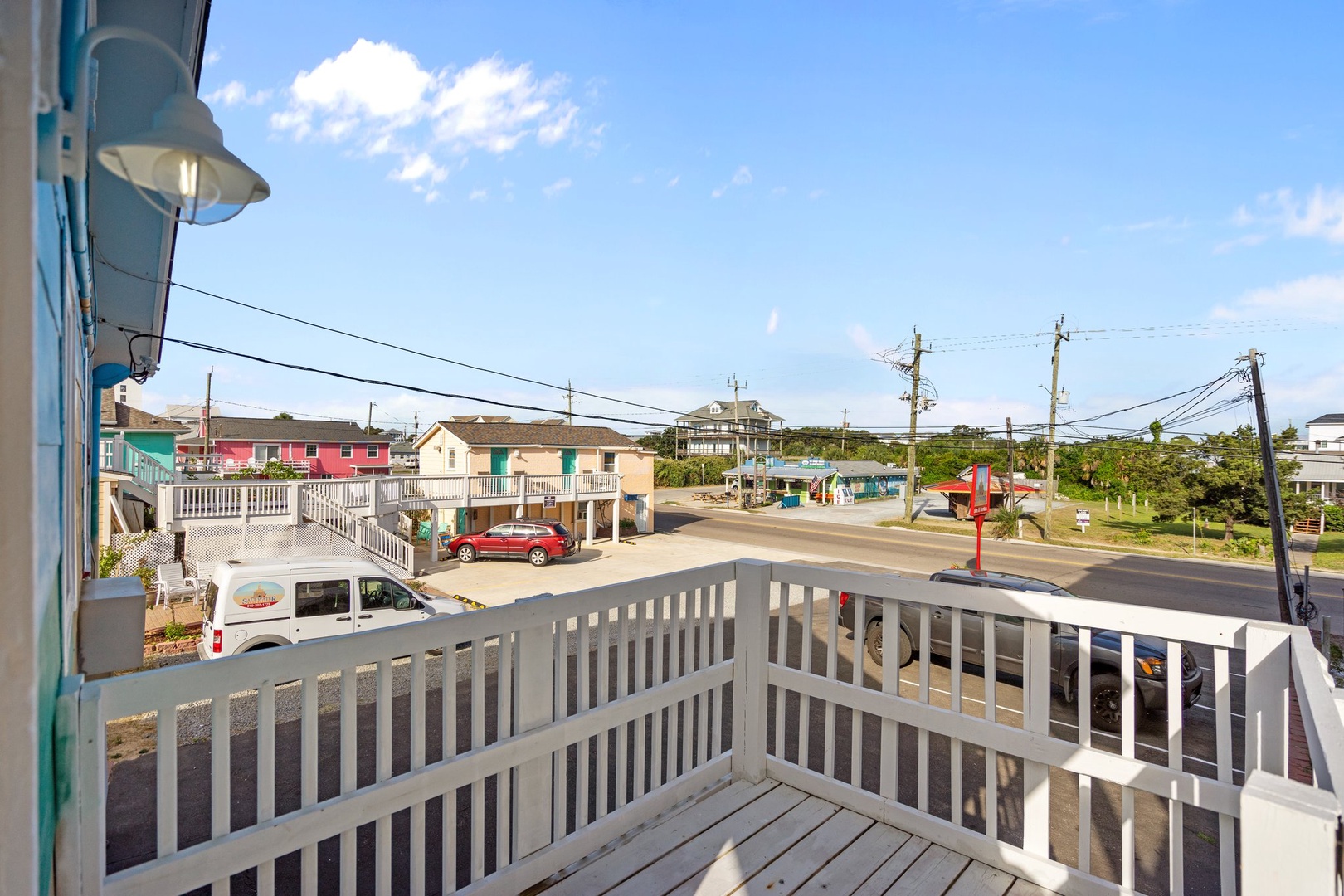 A quiet residential neighborhood stretches out beyond the property, featuring colorful beach houses and peaceful streets under sunny skies.